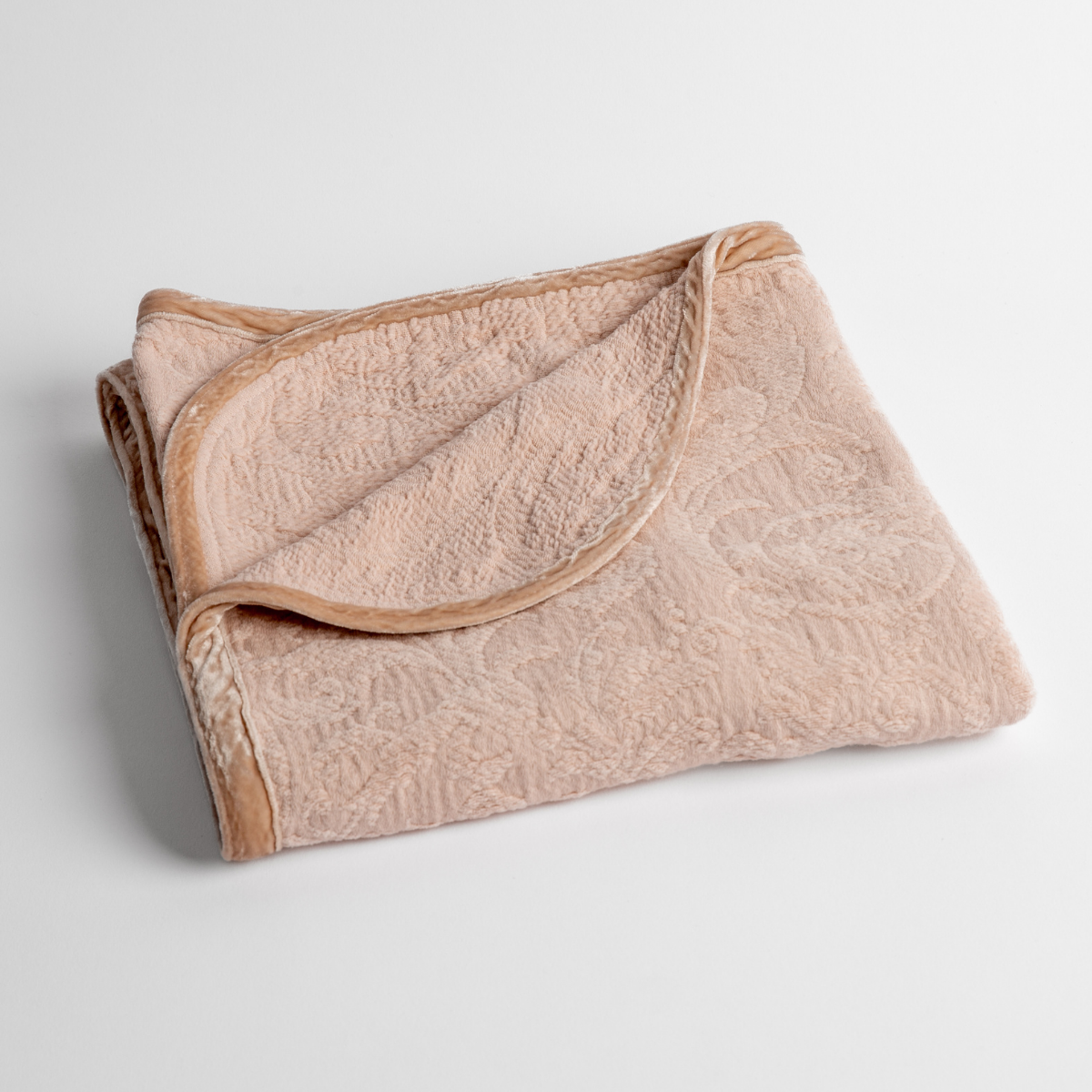Pearl: a folded blanket with the corner turned down to show the trim against a white background, shot from an overhead angle.