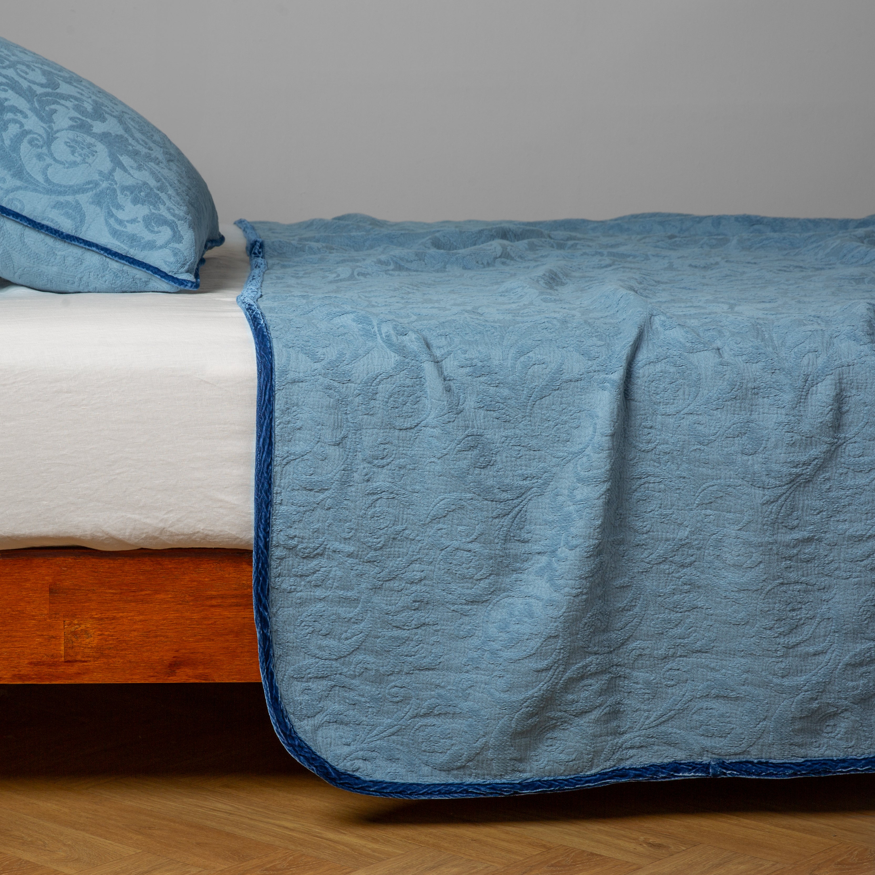 Tahoe Blue: a side view of a bed dressed in a winter white fitted sheet with matching coverlet and sham.