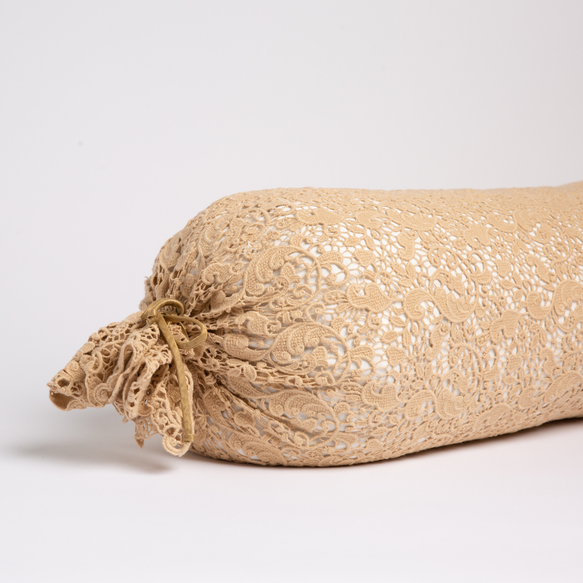 Honeycomb: one end of a lace boslter cover on a winter white liner against a white background.