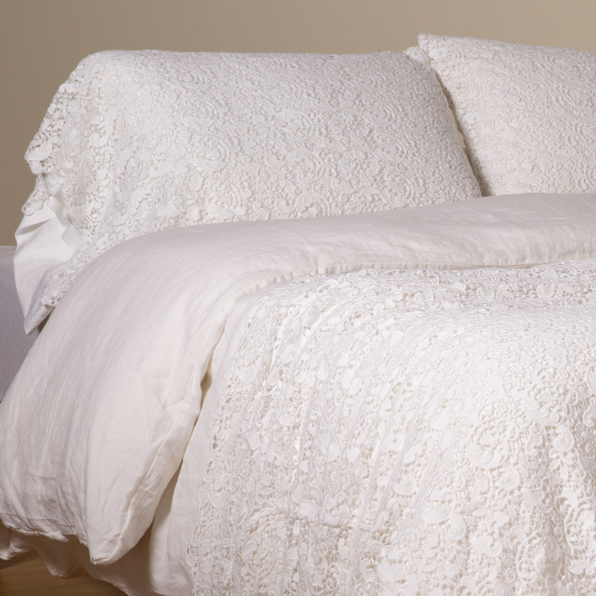 White: a pair of cotton lace pillowcase covers on winter white liners shown on a bed dressed in winter white linen with a matching cotton lace bed scarf.