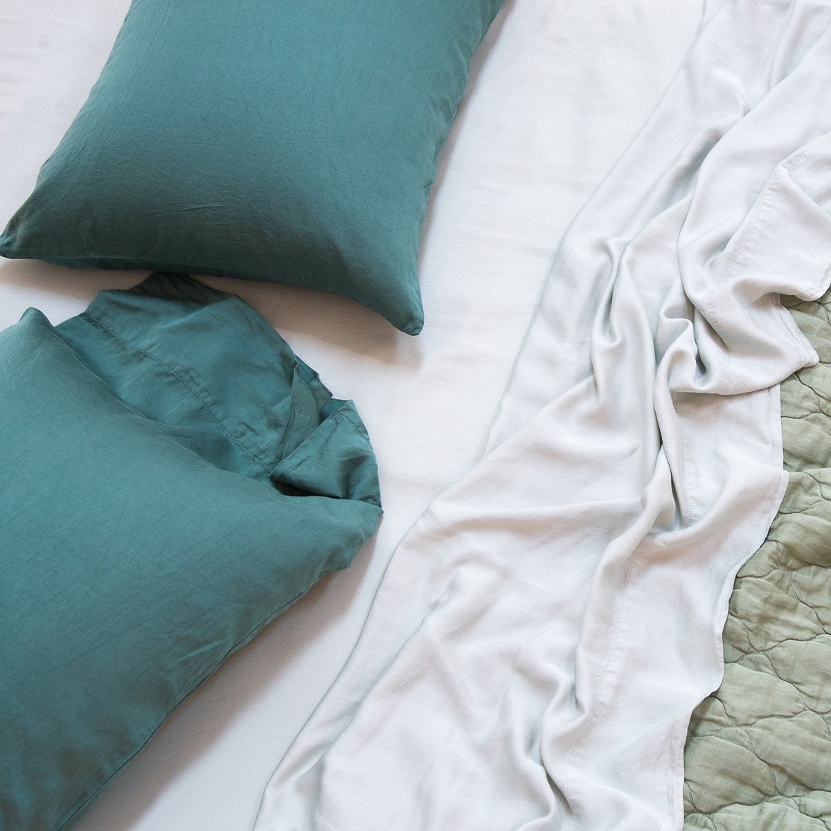 : Madera Luxe sleeping pillows and sheeting with a quilted Luna coverlet, in various shades of green - overhead view.