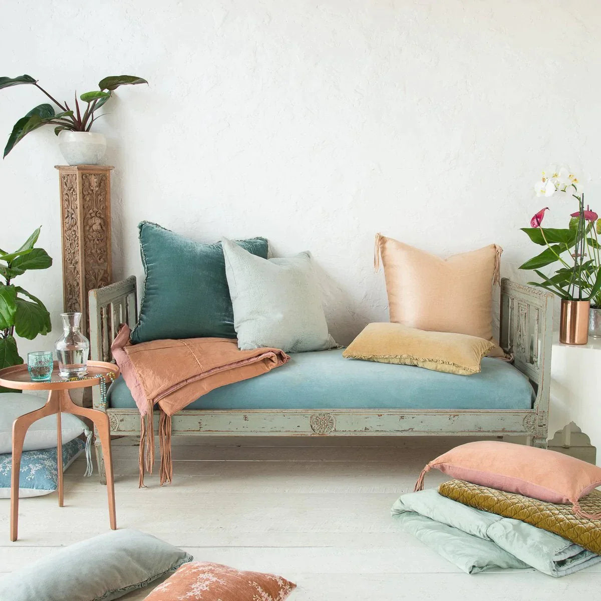 : Eucalyptus Carmen sham on a light blue antique day bed, layered with accessory pieces in pink and blue tones in linen and charmeuse. Styled with copper accents and greenery.