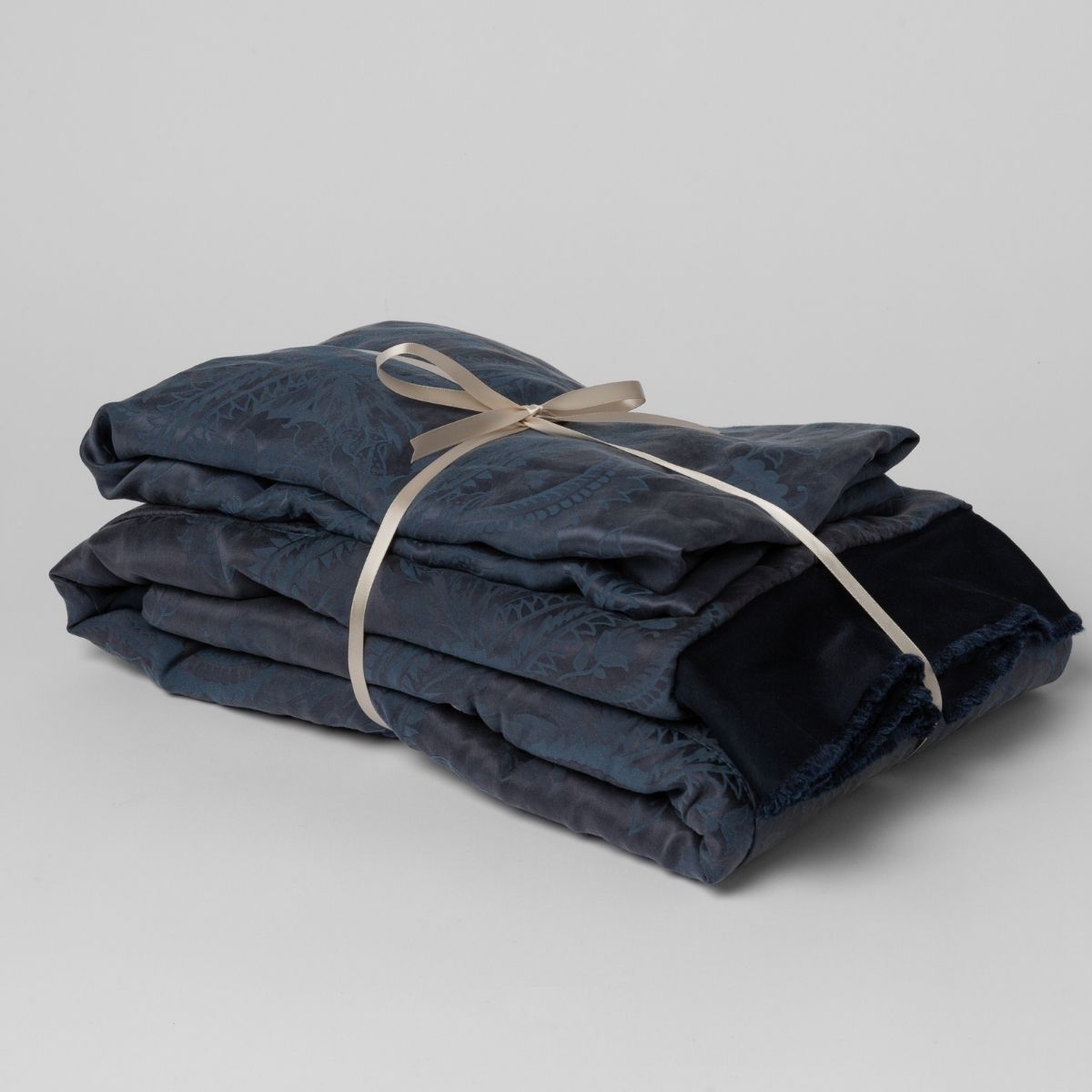 Midnight: matching crib sheet and baby blanket bundled and tied with a ribbon against a white background.