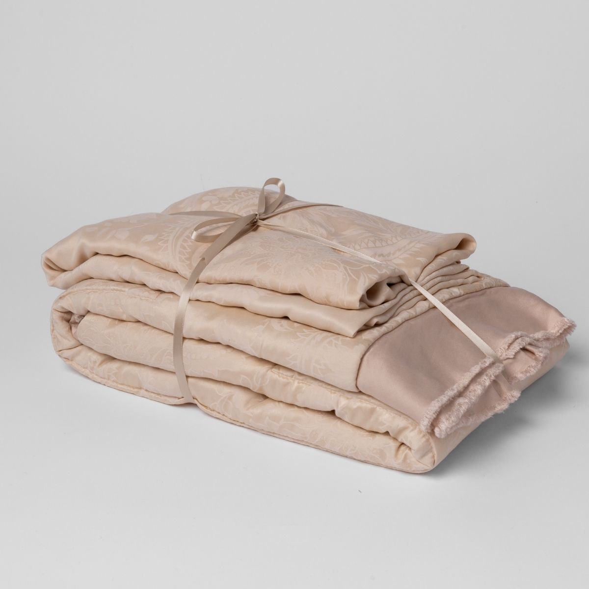 Pearl: matching crib sheet and baby blanket bundled and tied with a ribbon against a white background.