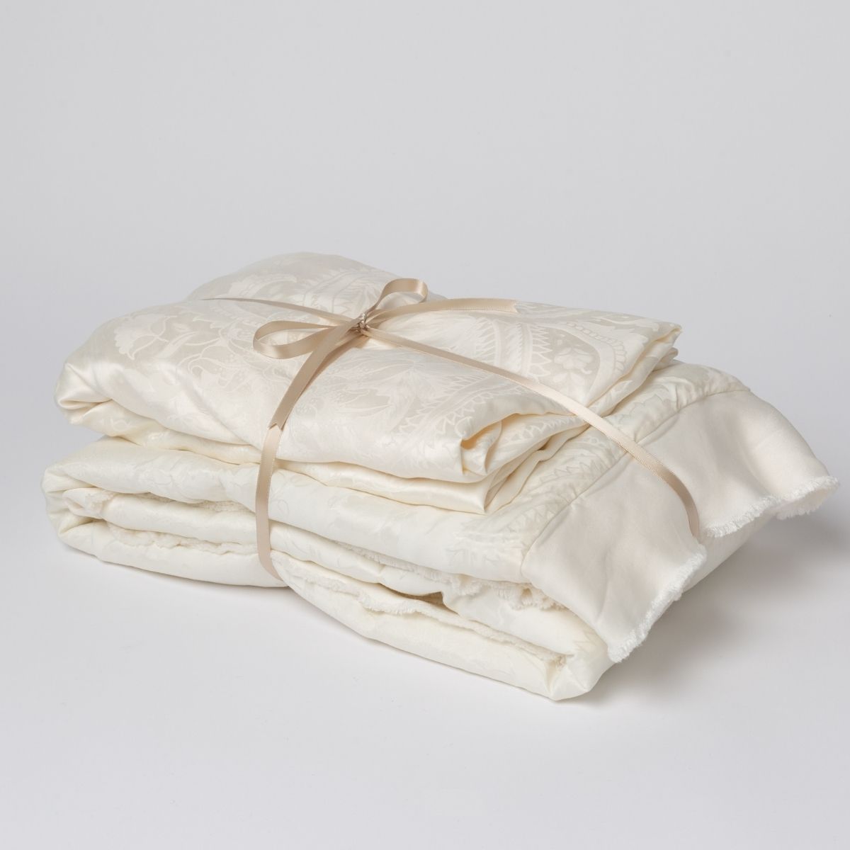 Winter White: matching crib sheet and baby blanket bundled and tied with a ribbon against a white background.