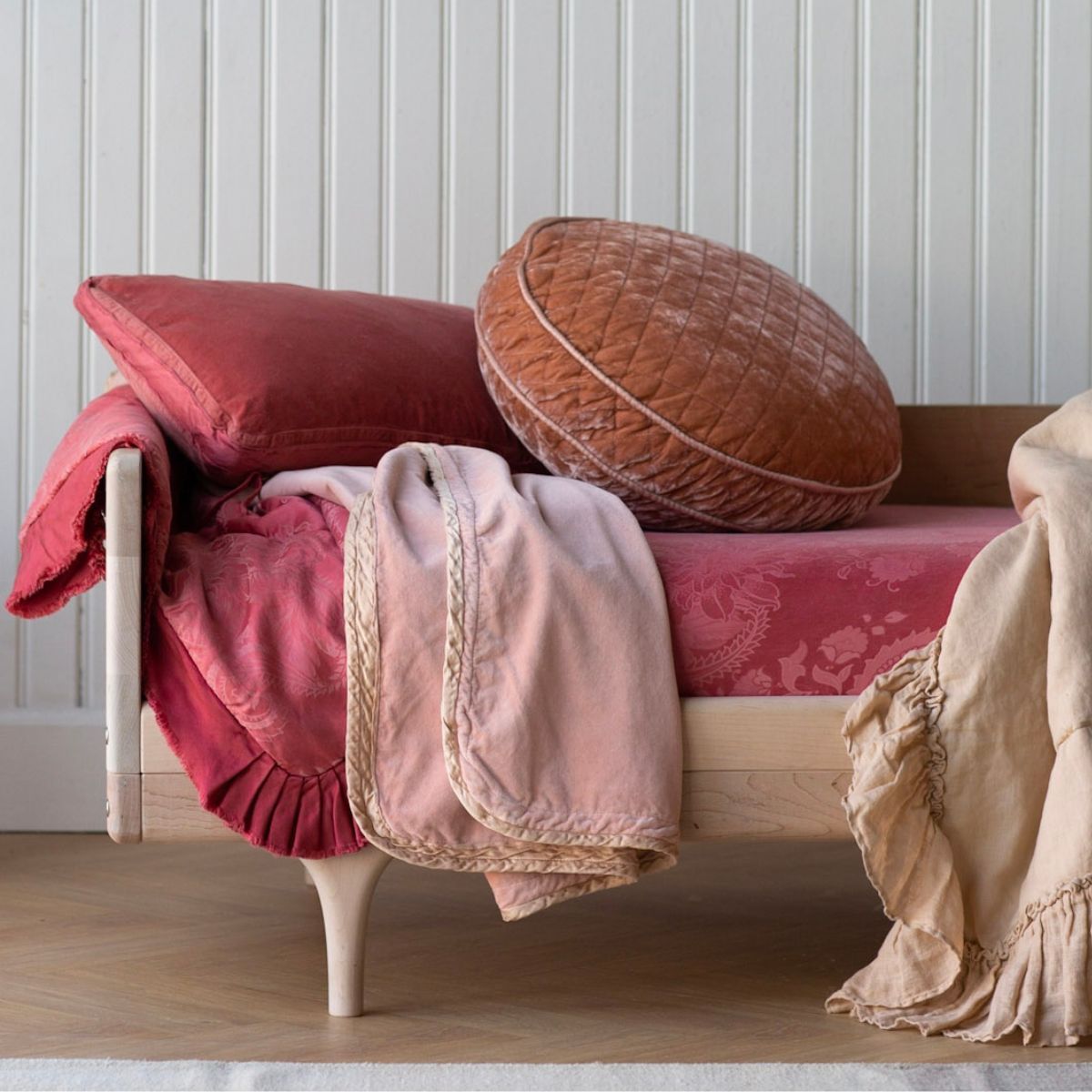 : a closeup of the end of a toddler bed dressed in feminime colors.