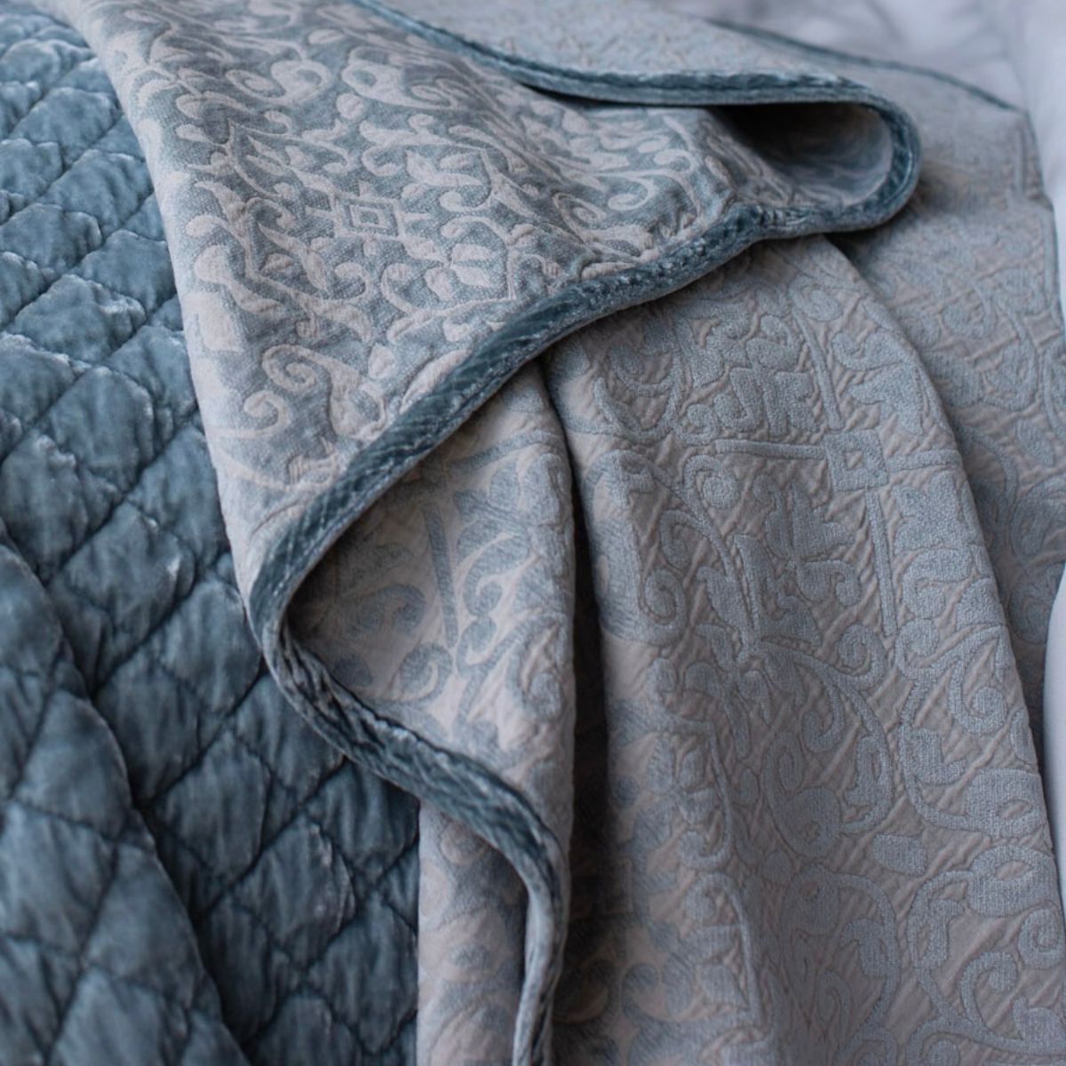 : cotton chenille baby blanket shown draped off of bed highlighting the trim detail and chenille pattern.
