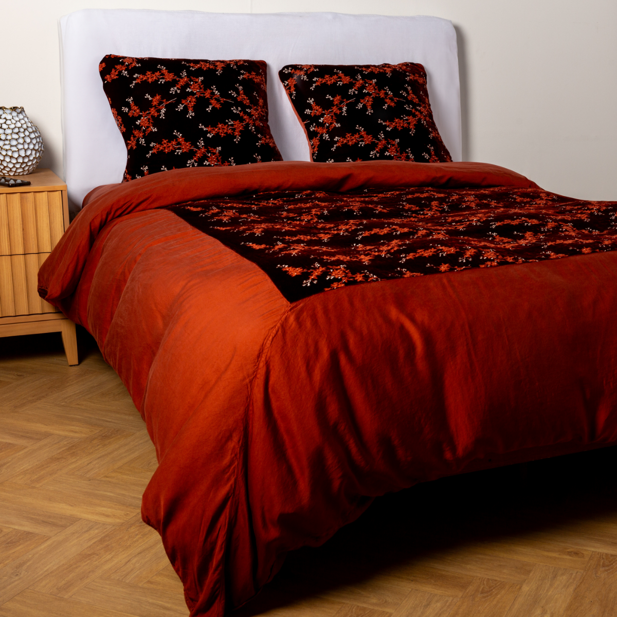 Autumn: A ¾ angle shot of an embroidered silk velvet and tencel duvet cover and matching shams with a vase and cell phone on the side table.