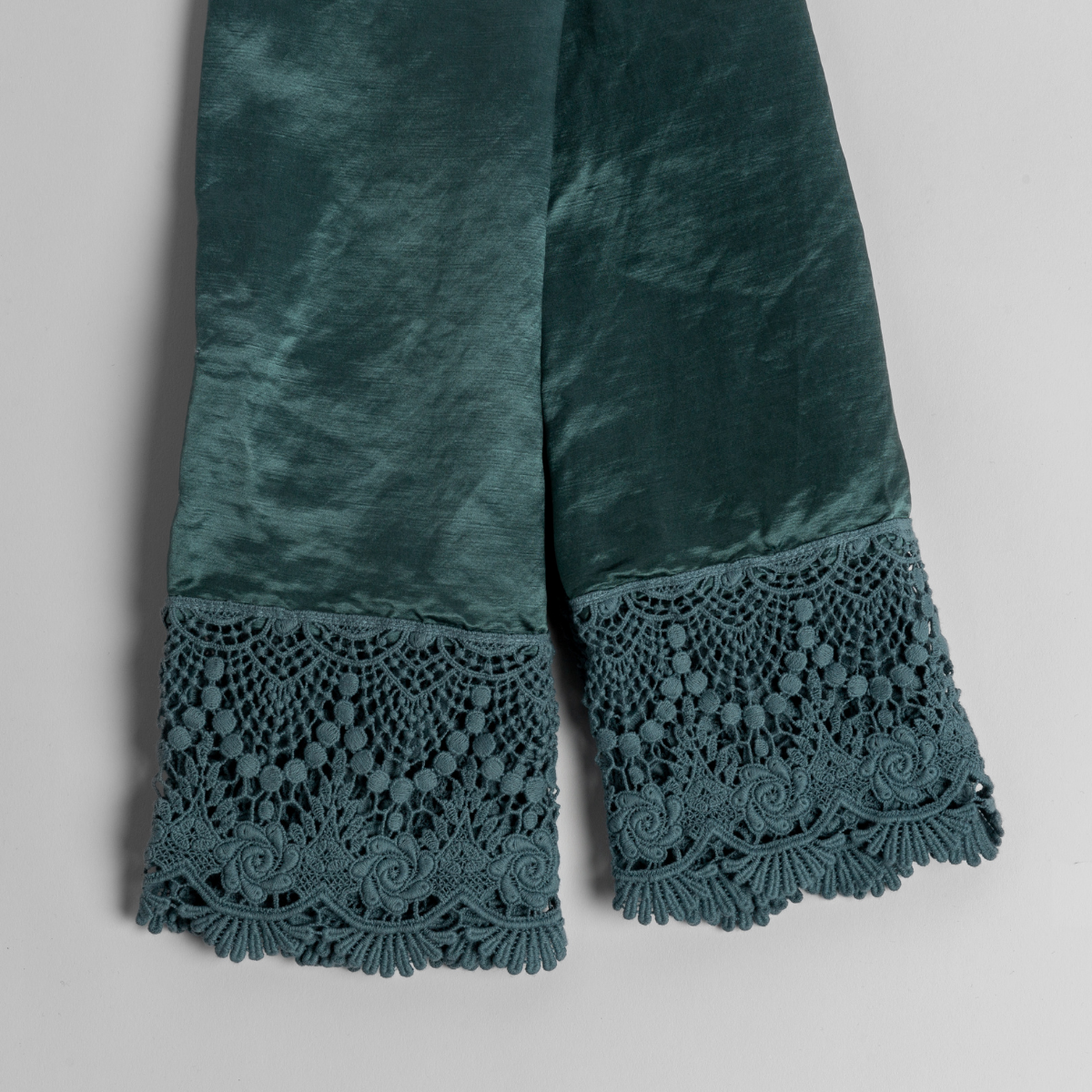 A pair of folded lace trimmed charmeuse pillowcases shot from overhead against a white background.