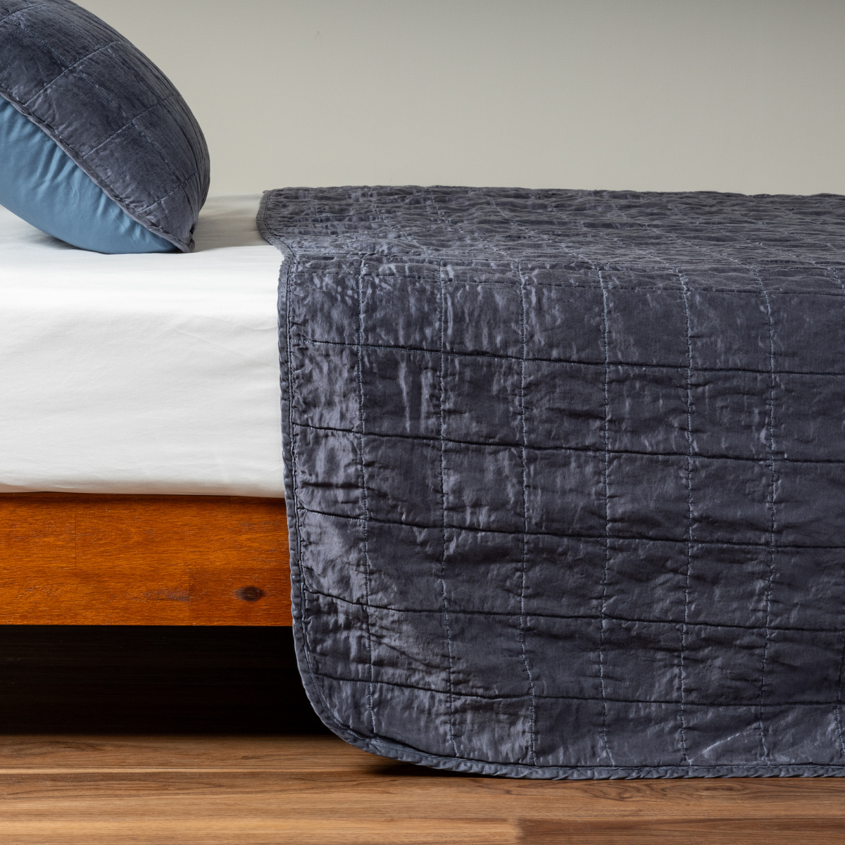Midnight: A side shot of a square quilted charmeuse coverlet in midnight, a rich indigo tone, with its matching sham.