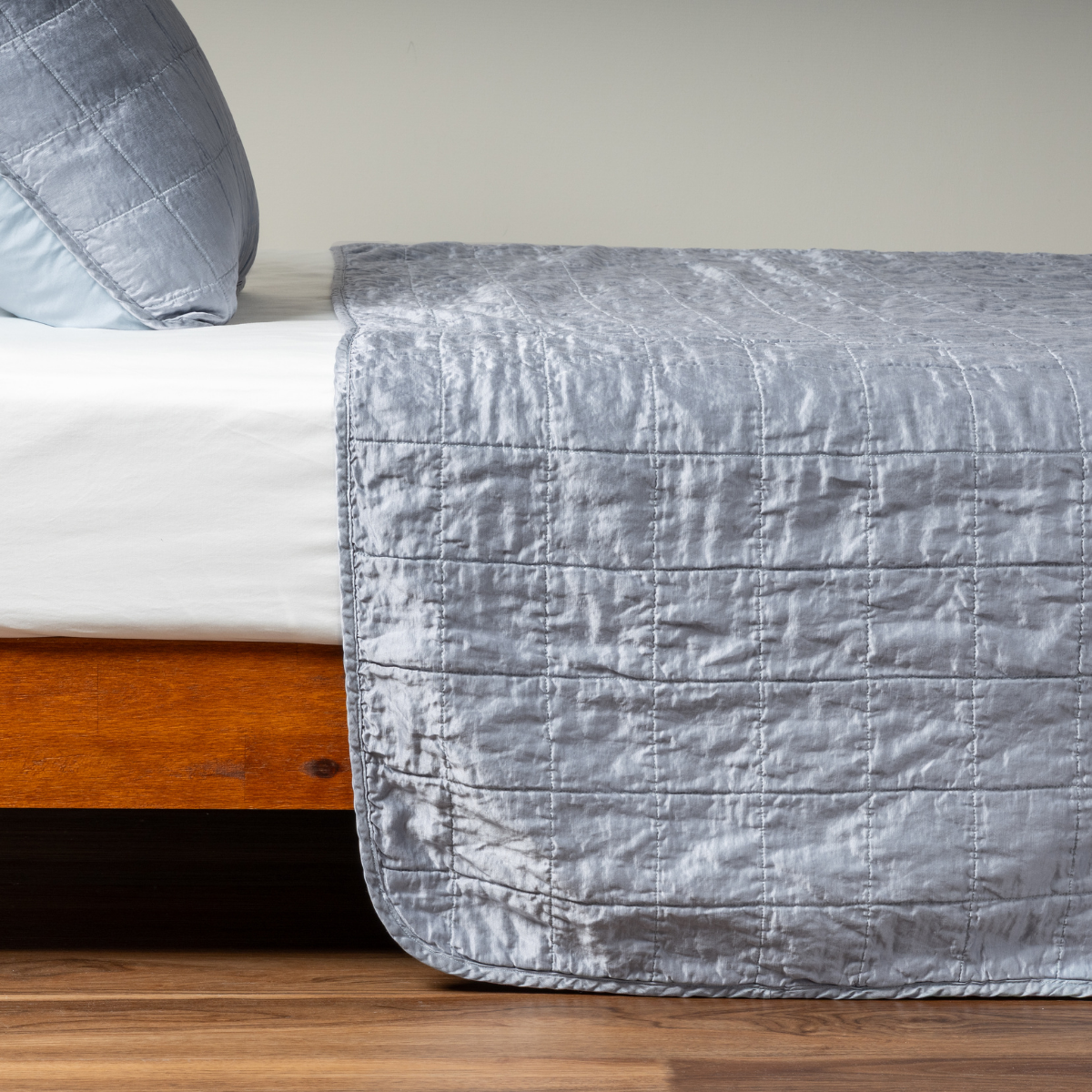 Tahoe Blue: A side shot of a square quilted charmeuse coverlet in tahoe blue, a crisp true blue, with its matching sham.
