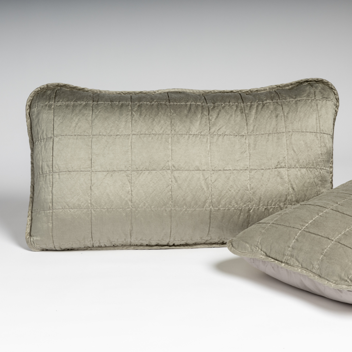 Fog: A pair of shams shown in fog, a soft mid-tone grey, against a white background with one sham upright and the other on its side to show the cotton sateen back and square-quilted charmeuse front.