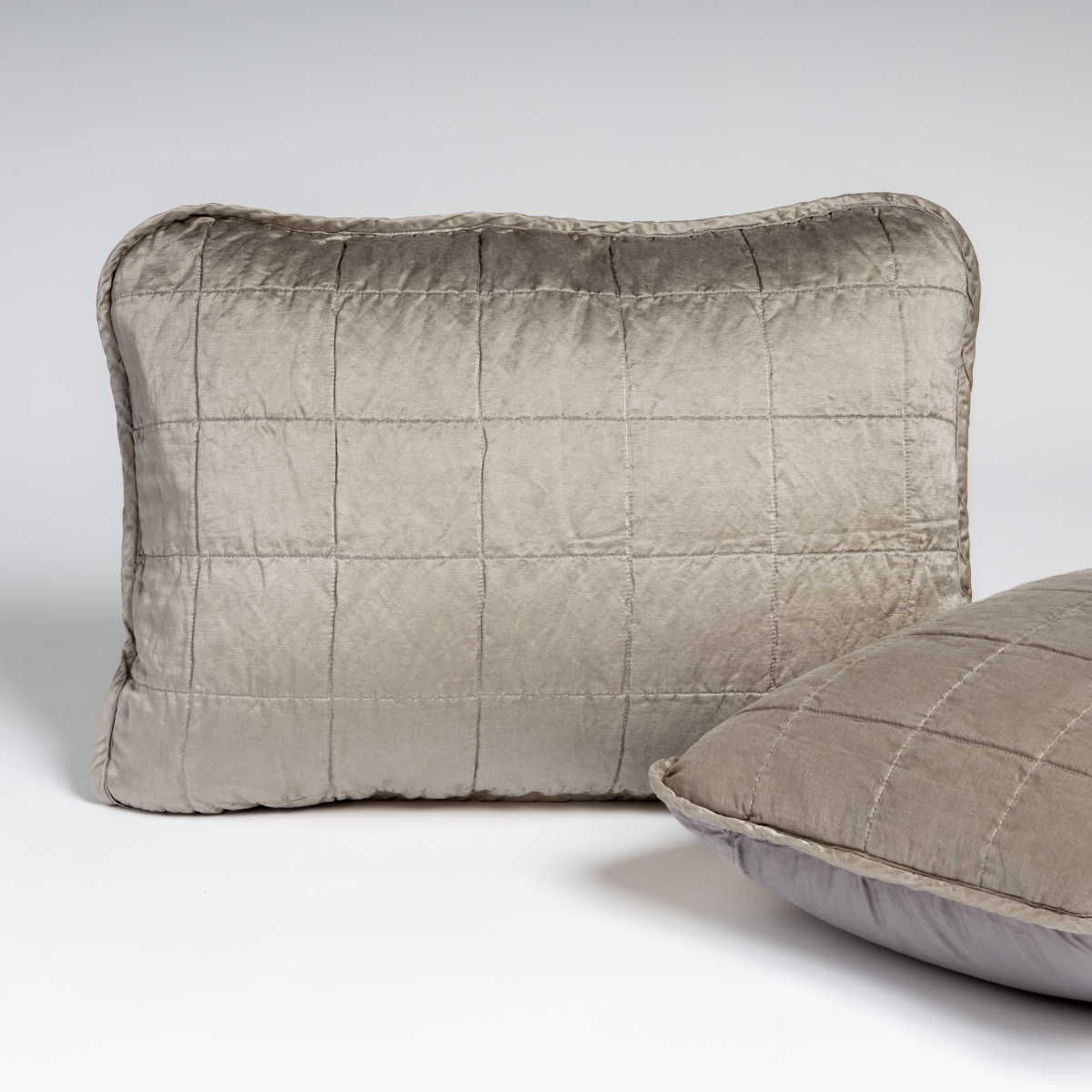 Moonlight: A pair of shams in moonlight, a saturated, cool, mid-dark grey tone, shown against a white background with one sham upright and the other on its side to show the cotton sateen back and square-quilted charmeuse front.