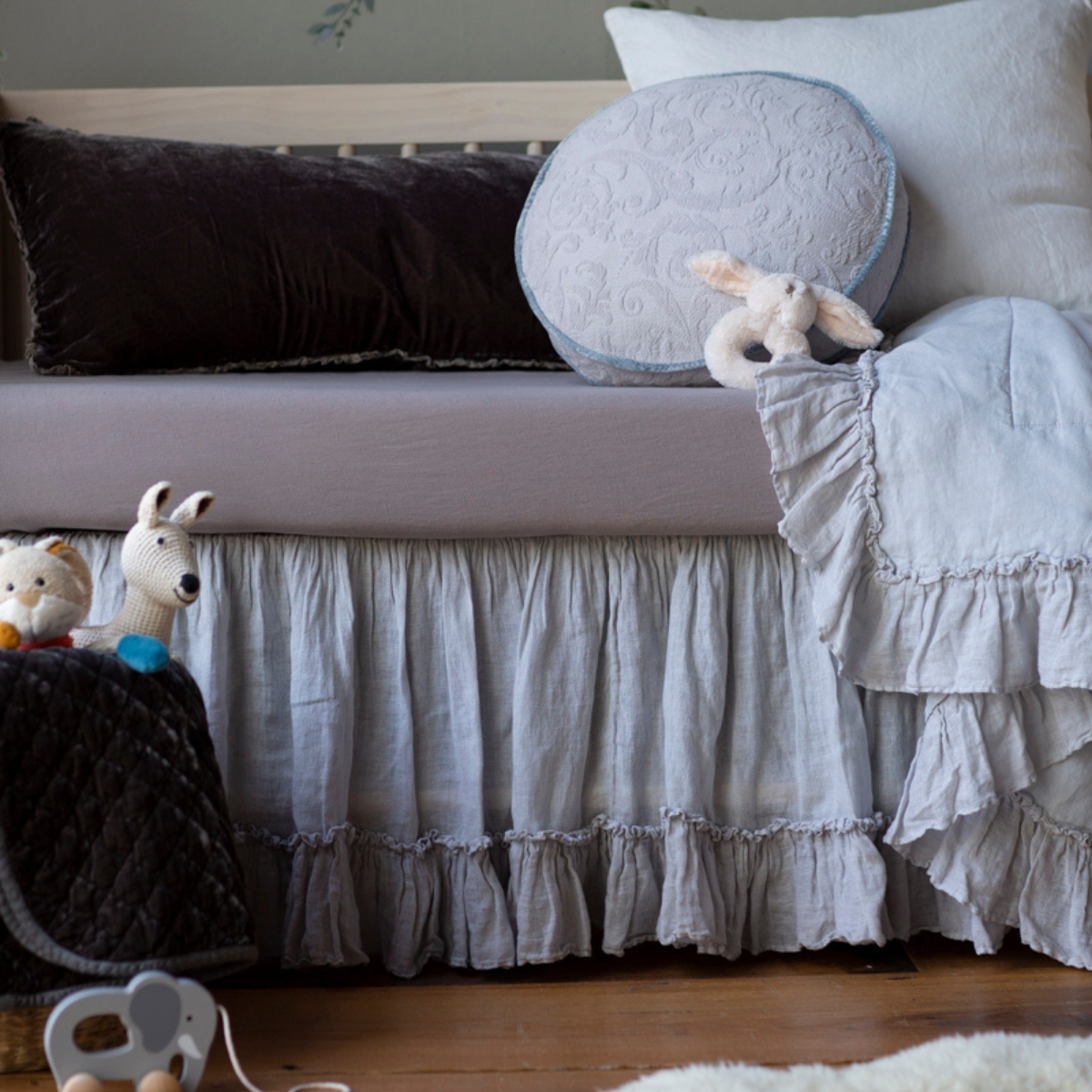 : Close up of crib sheet in moonlight shown with light blue bedding and a small white stuffed bunny.