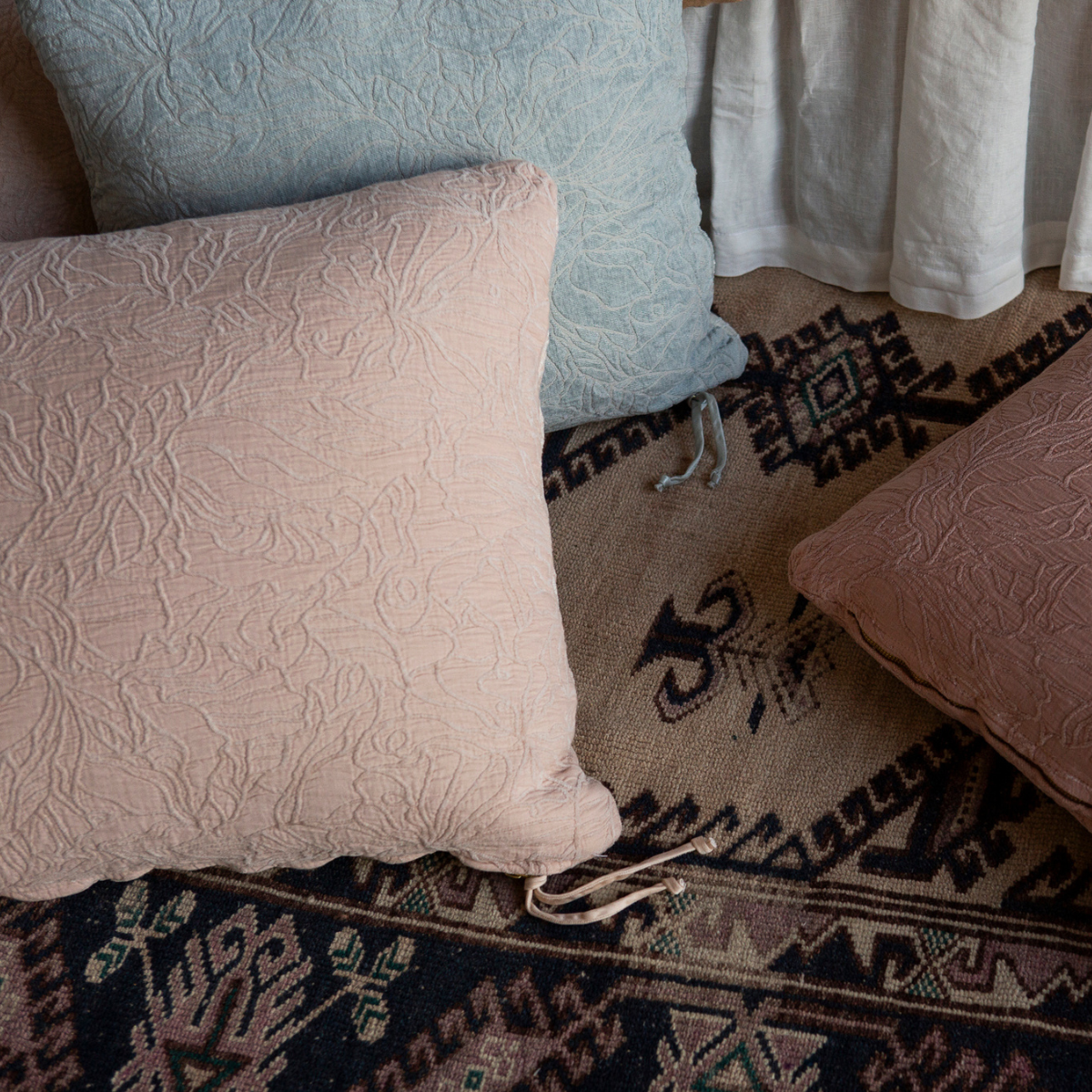 chenille and cotton jacquard throw pillows shown from overhead against a colorful rug