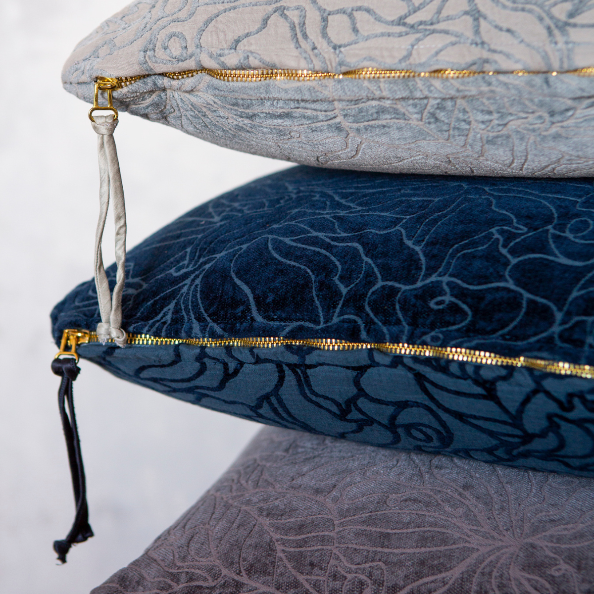chenille and cotton jacquard throw pillows stacked and showing the detail of the textile as well as the dangling zipper pulls
