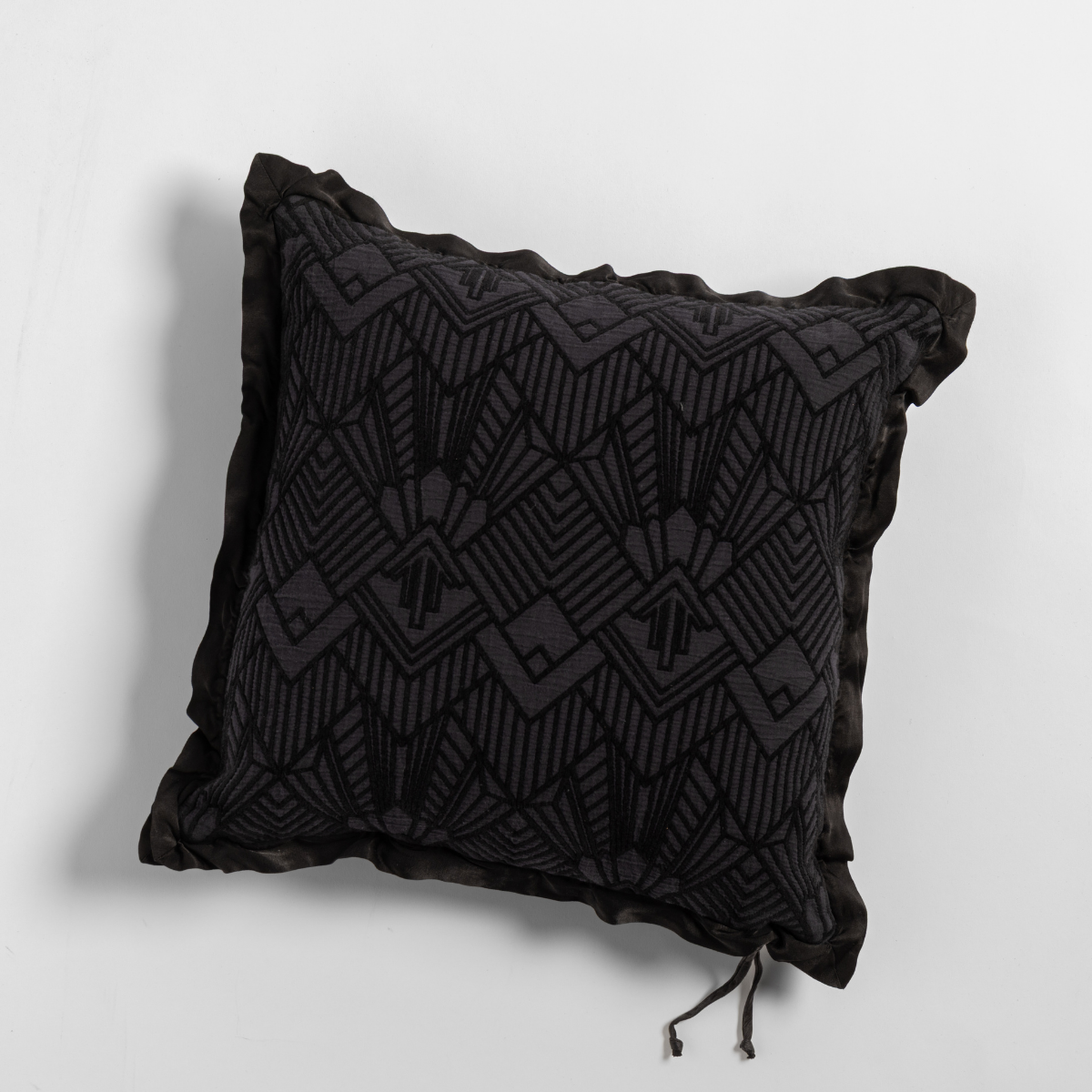 Corvino: The cotton jacquard side of a textured throw pillow with contrasting ruffled edges, shot from overhead against a plain background.