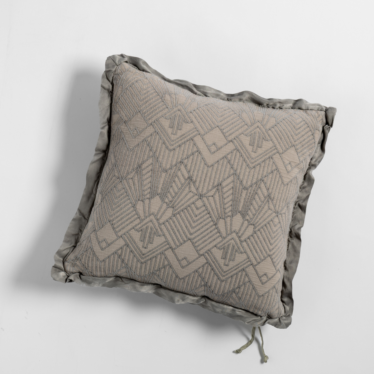Fog: The cotton jacquard side of a textured throw pillow with contrasting ruffled edges, shot from overhead against a plain background.