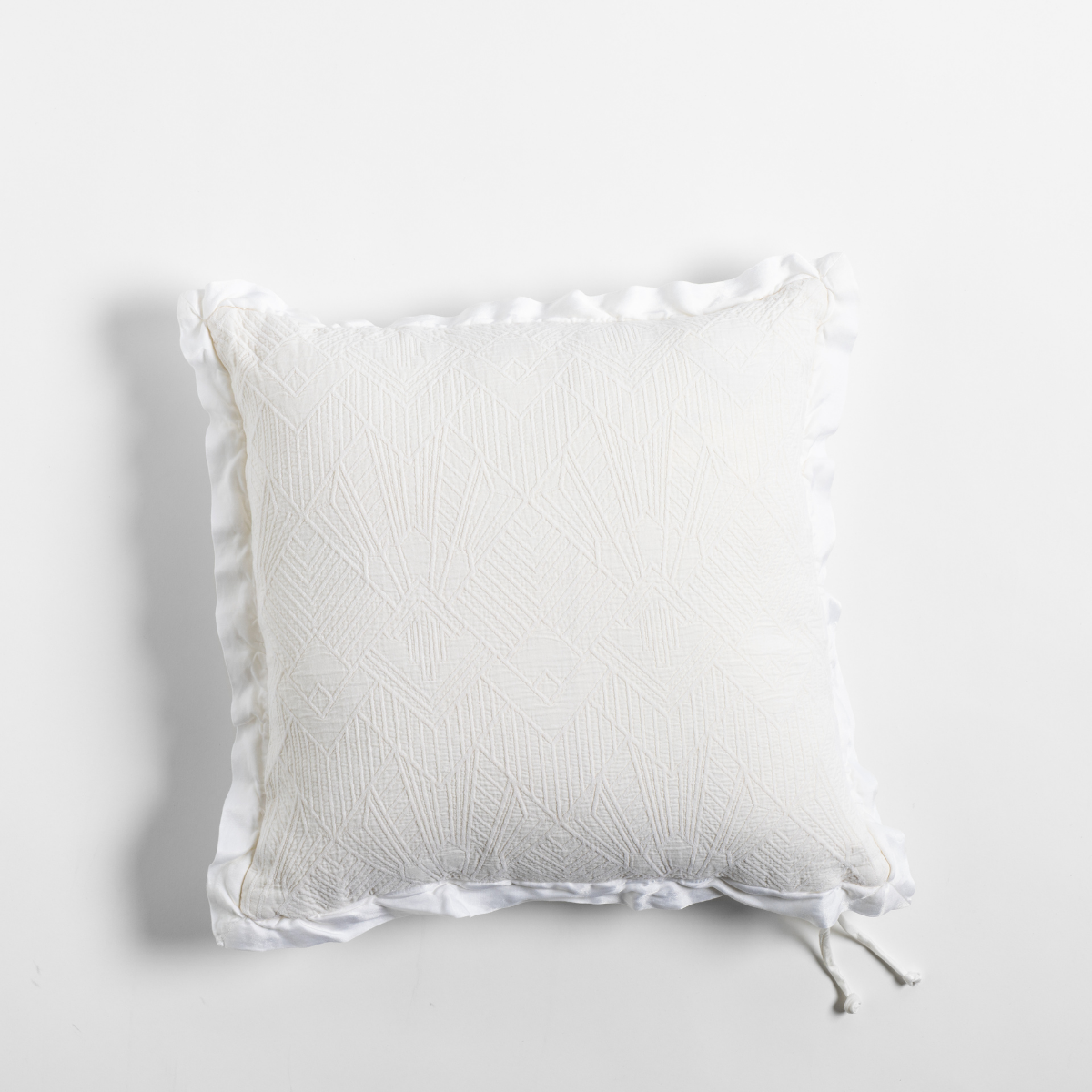 Winter White: The cotton jacquard side of a textured throw pillow with contrasting ruffled edges, shot from overhead against a plain background.