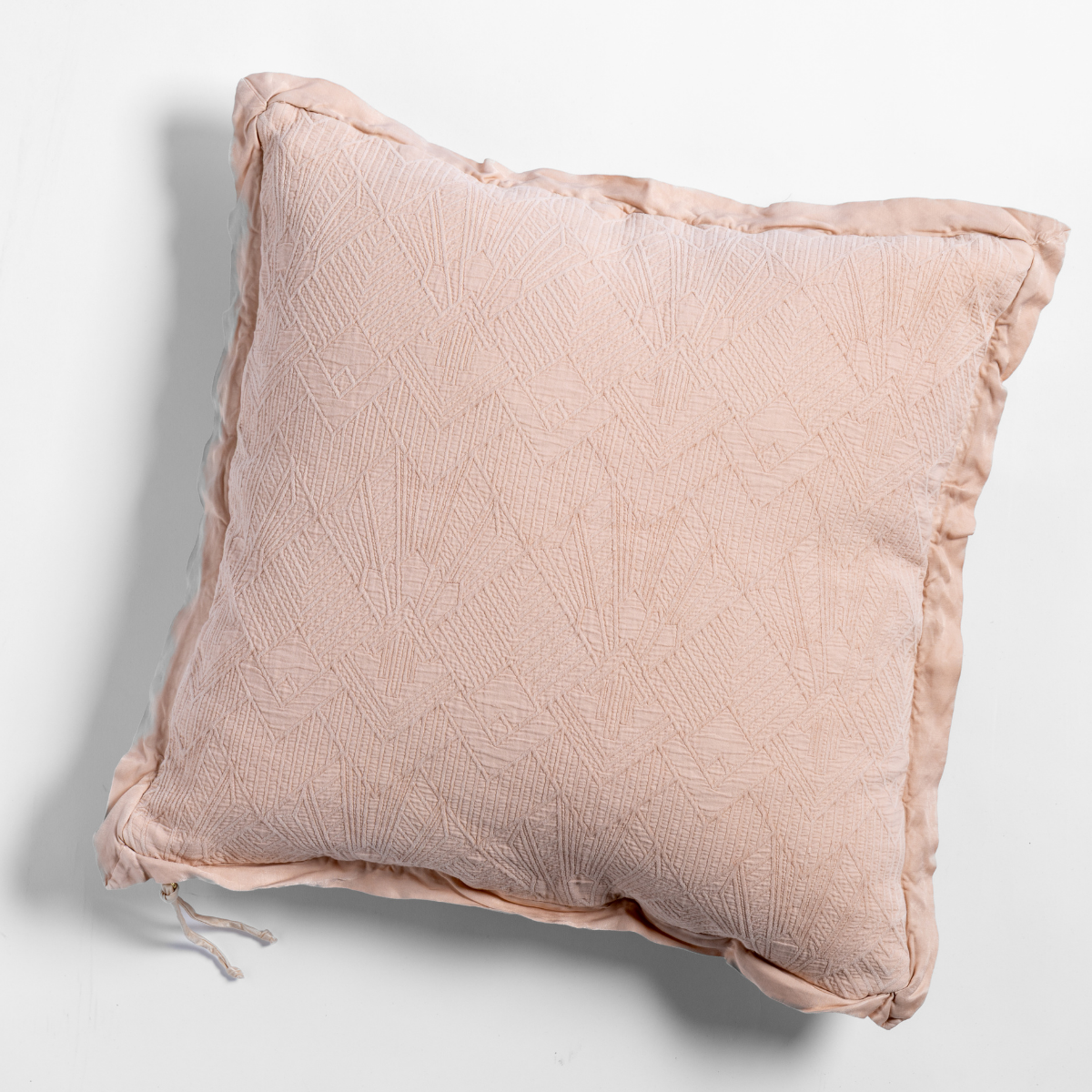 Pearl: The cotton jacquard side of a textured throw pillow with contrasting ruffled edges, shot from overhead against a plain background.