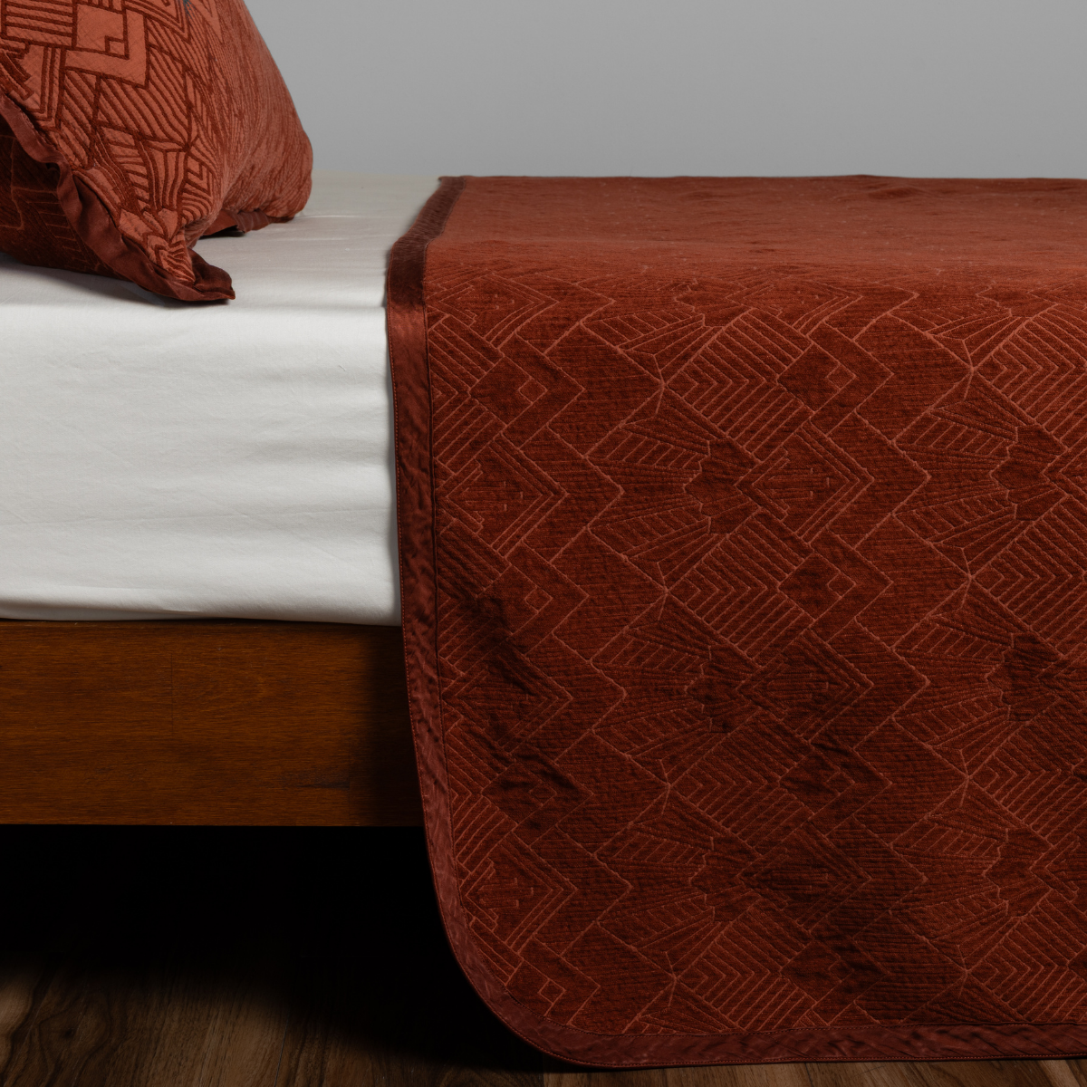 Autumn: textured bedspread on a bed with wooden bedframe.
