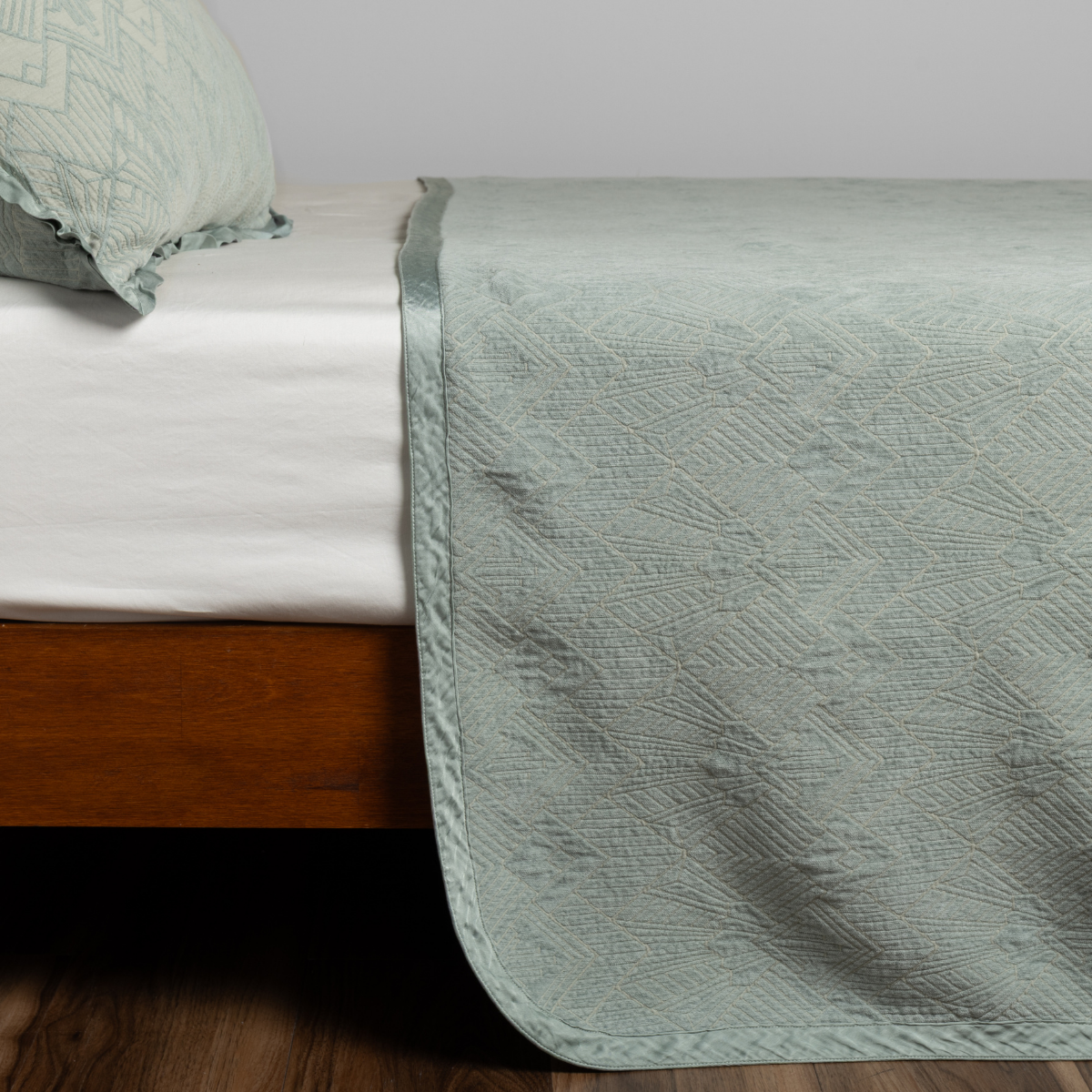Eucalyptus: textured bedspread on a bed with wooden bedframe.
