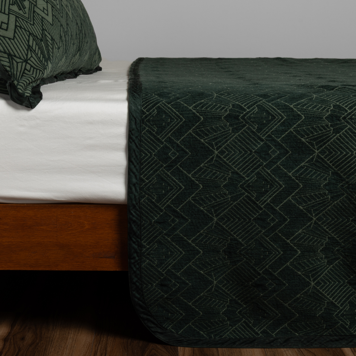 Juniper: textured bedspread on a bed with wooden bedframe.