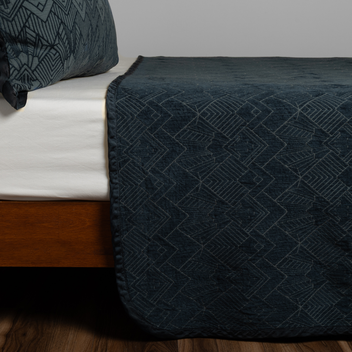 Midnight: textured bedspread on a bed with wooden bedframe.