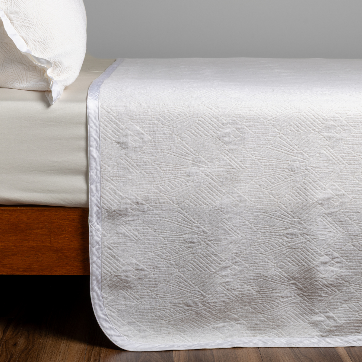 Winter White: textured bedspread on a bed with wooden bedframe.