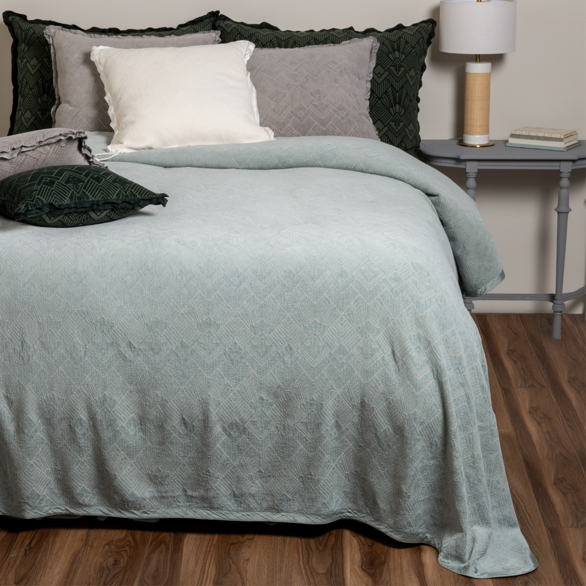 : Bed with green bedspread and pillows in a bedroom setting
