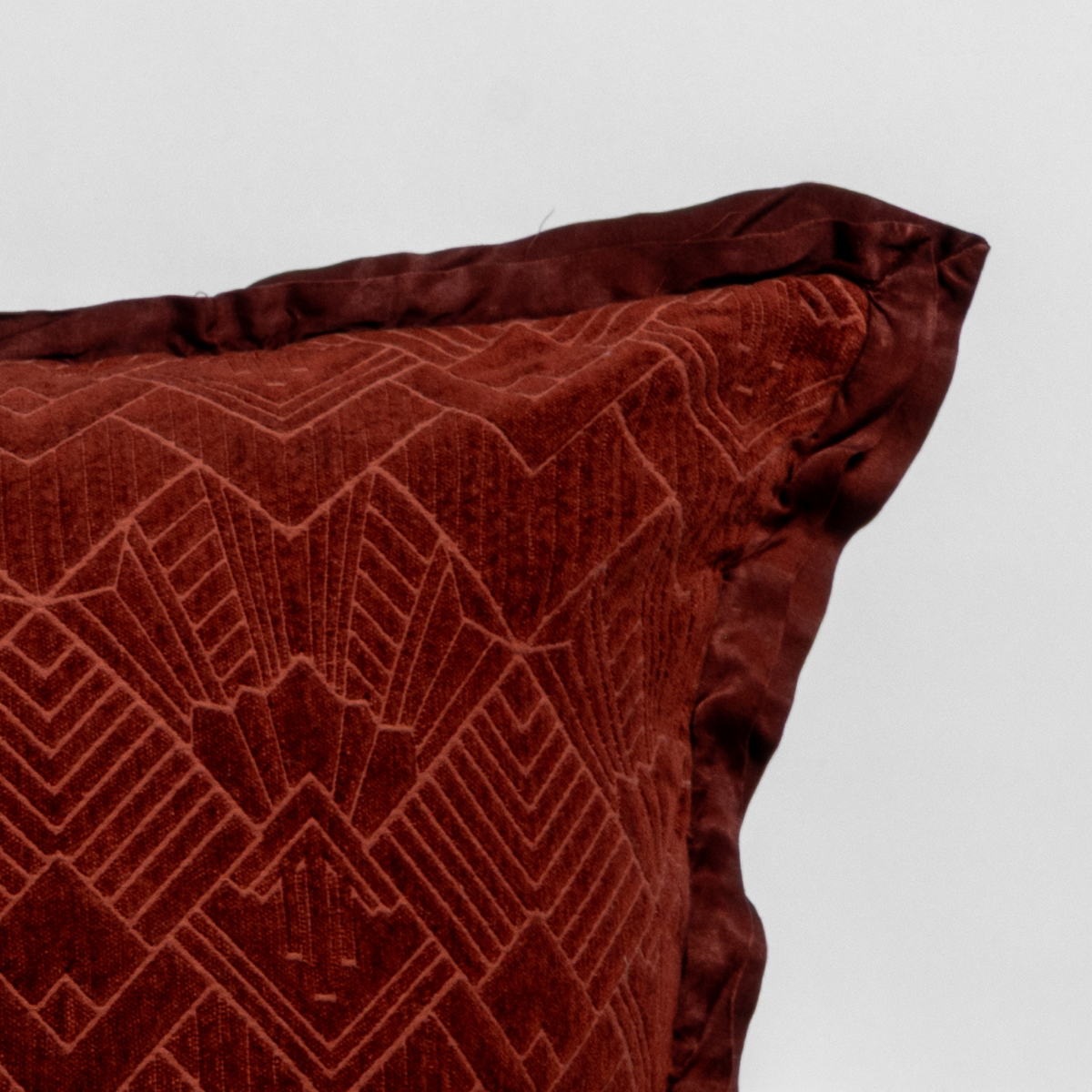 Autumn: Close-up of a textured pillow sham corner with a satin ruffle, shot against a plain background.