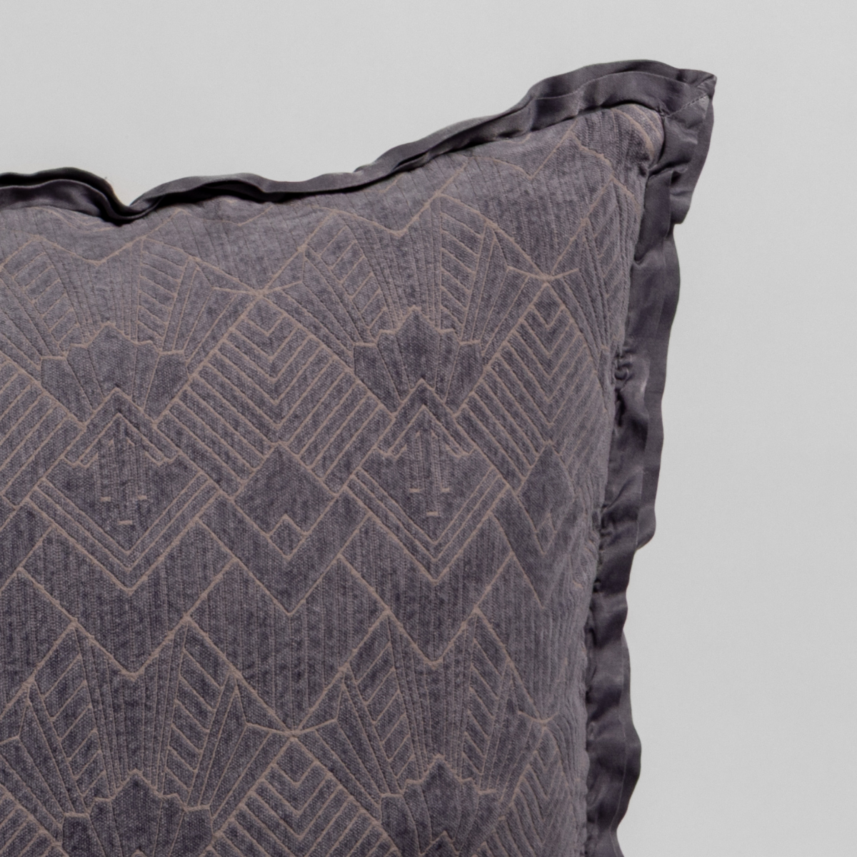 French Lavender: Close-up of a textured pillow sham corner with a satin ruffle, shot against a plain background.