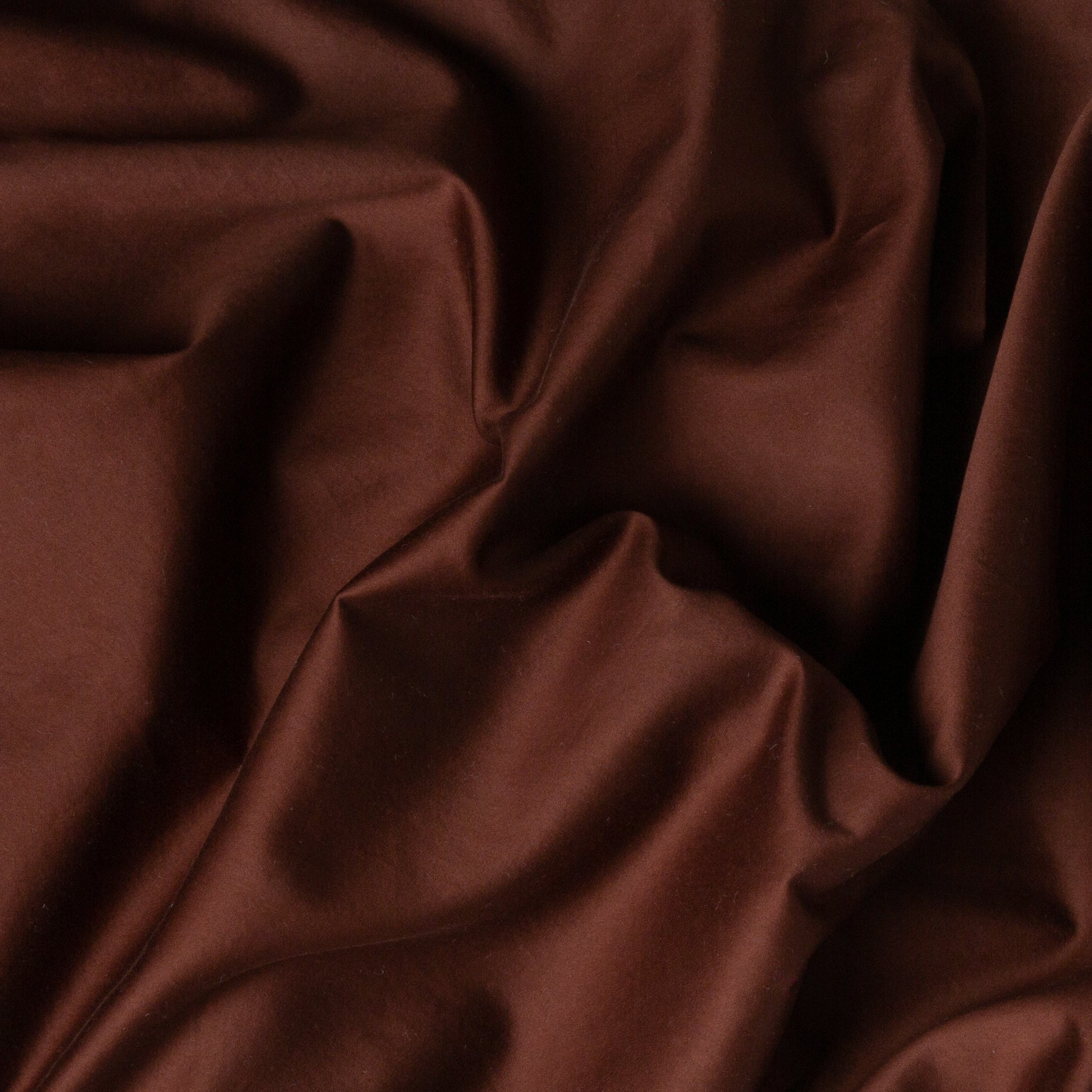 A close up of cotton sateen fabric in mahogany, a deep, earthen, reddish brown.