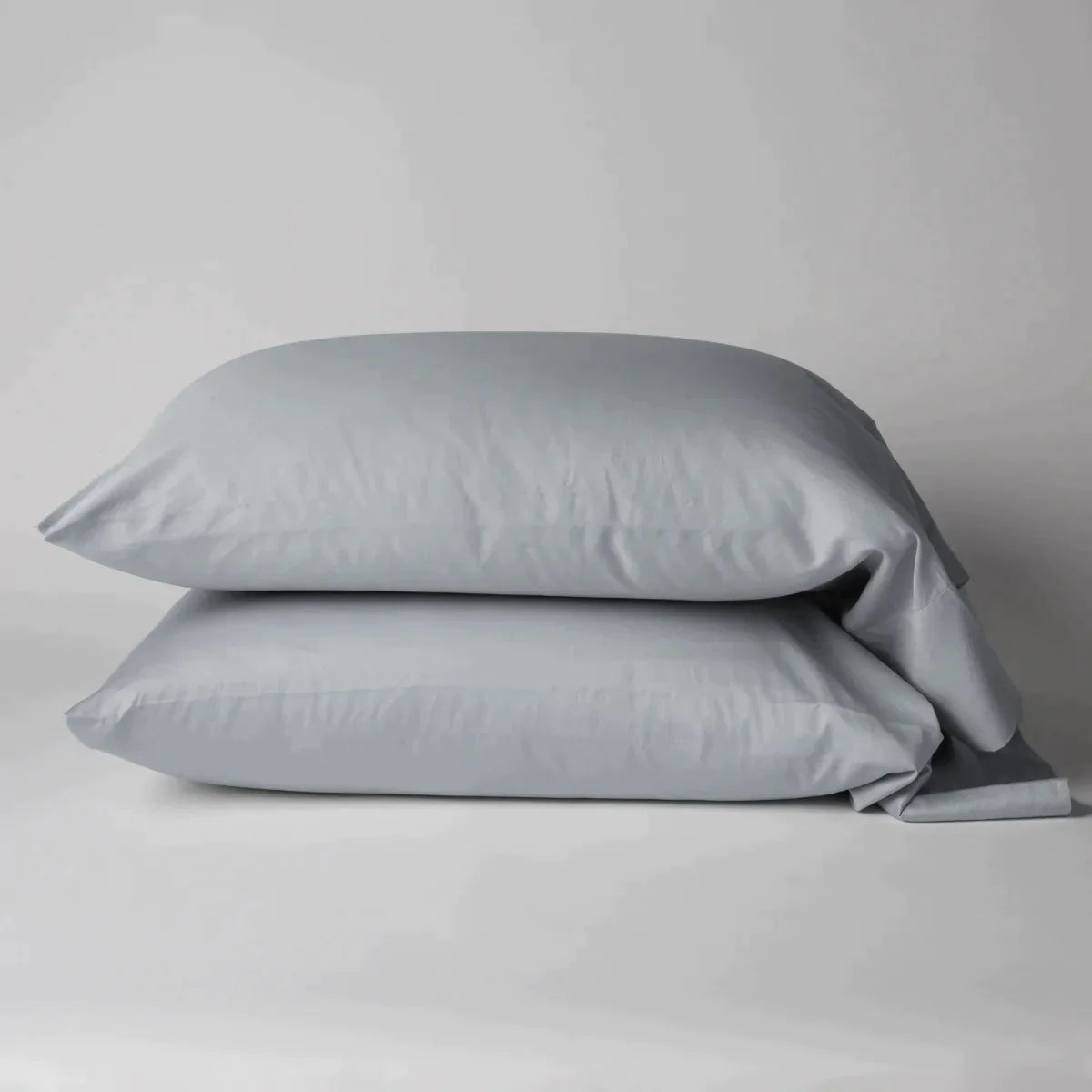 Cloud: Two cotton sateen sleeping pillows, stacked neatly against a white backdrop - side view.