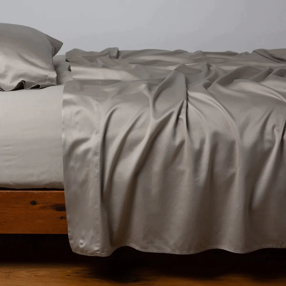 Fog: Cotton sateen sleeping pillow, on a bed with matching sheets - side view.