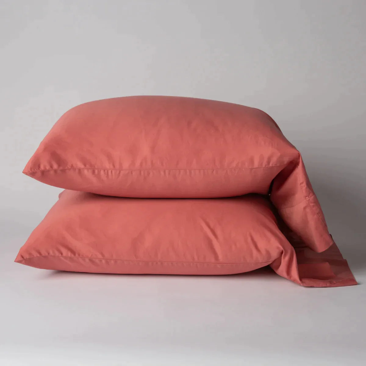 Poppy: Two cotton sateen sleeping pillows, stacked neatly against a white backdrop - side view.
