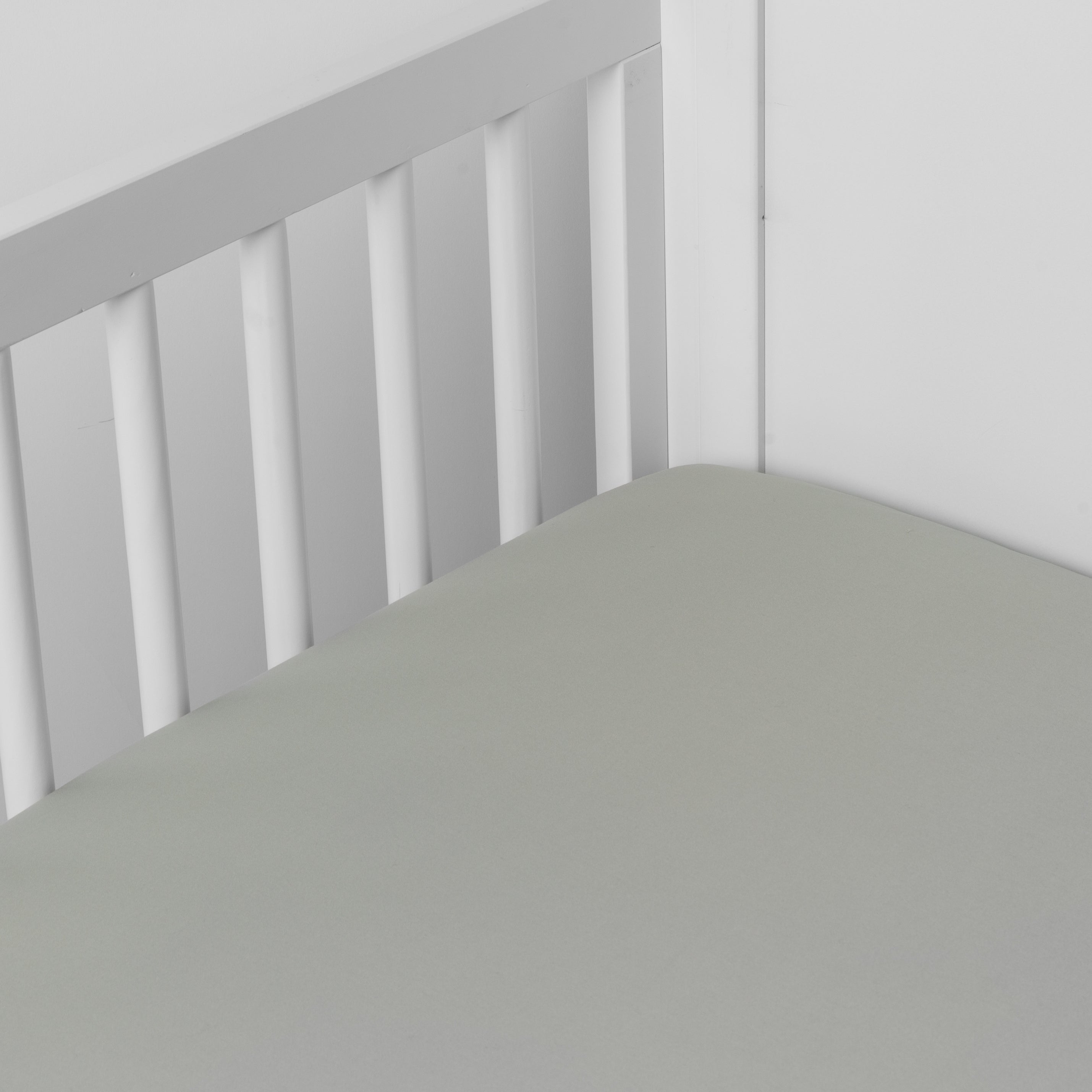 Eucalyptus: Cotton sateen crib sheet shown from a slight overhead angle into an inside corner of a crib.