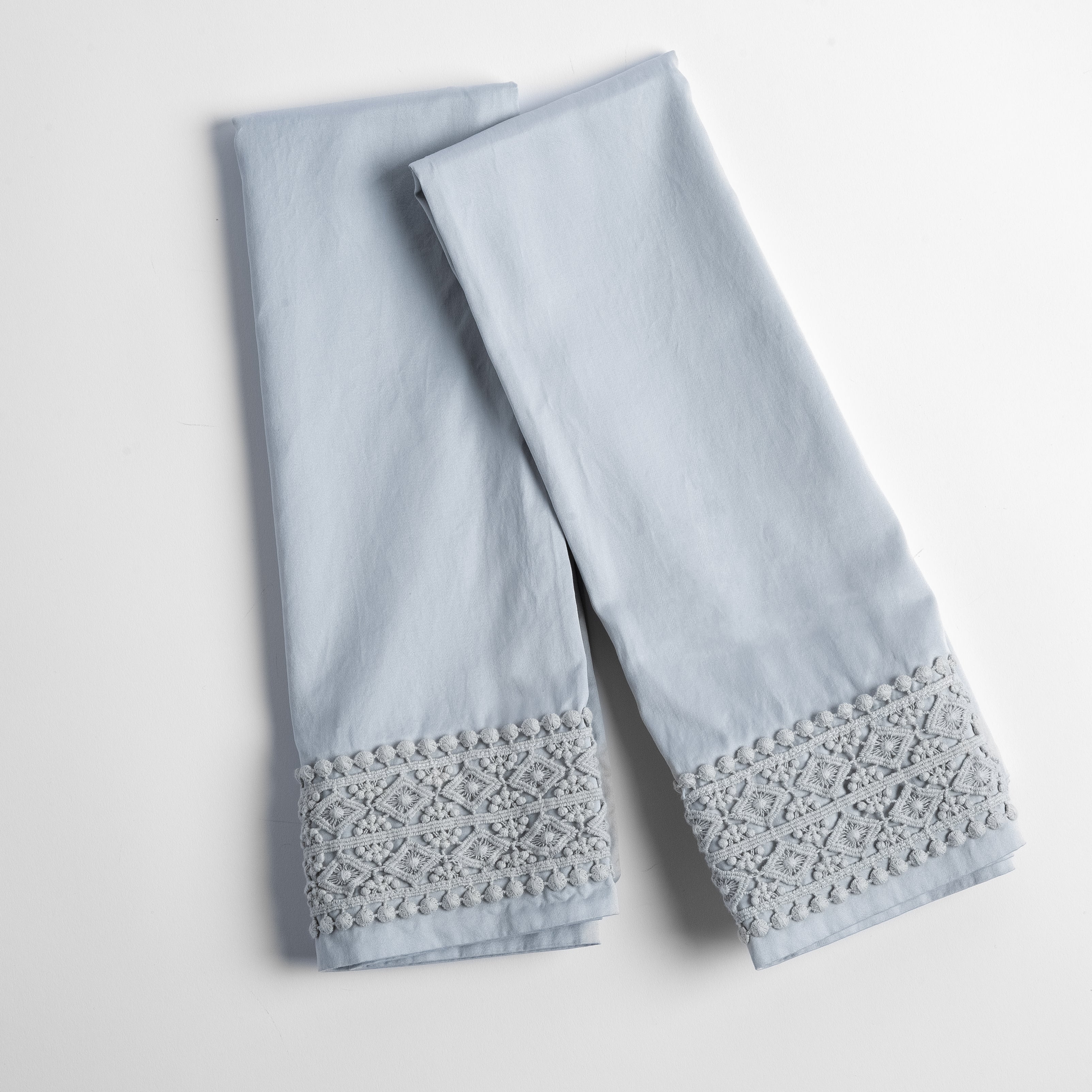 An overhead shot of a folded pair of lace trimmed pillowcases shown side by side and slightly overlapping.