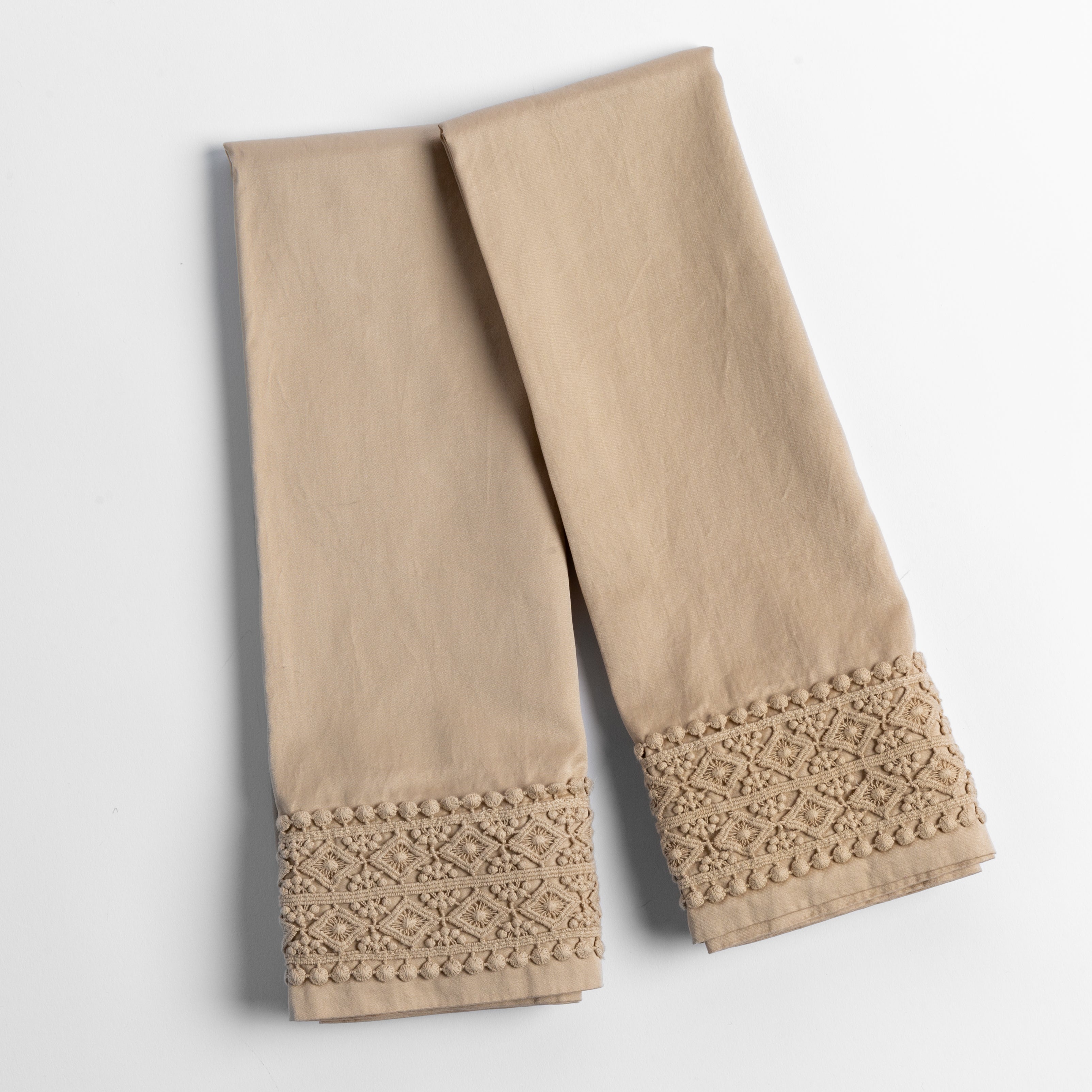 An overhead shot of a folded pair of lace trimmed pillowcases shown side by side and slightly overlapping.