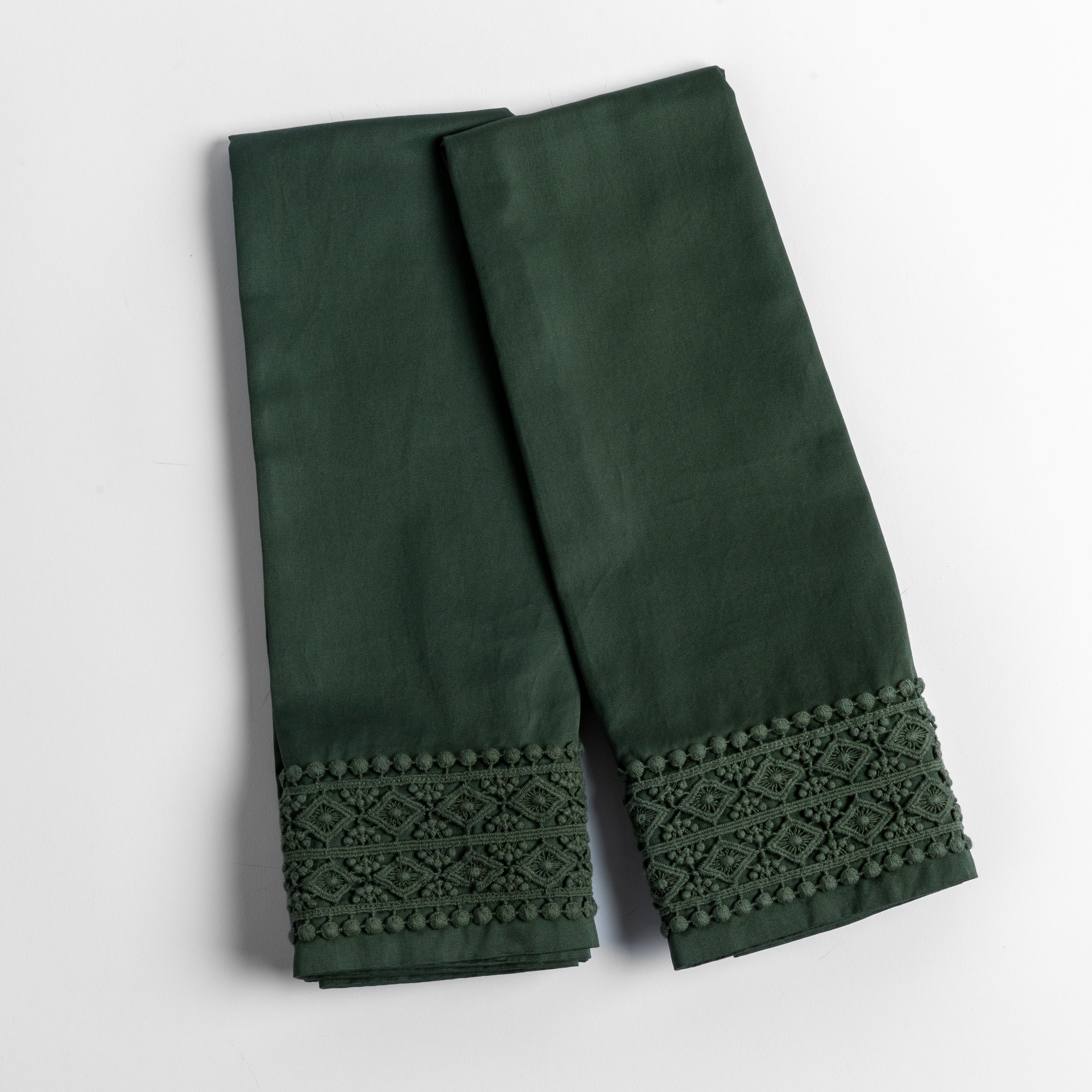 Juniper: An overhead shot of a folded pair of lace trimmed pillowcases shown side by side and slightly overlapping.