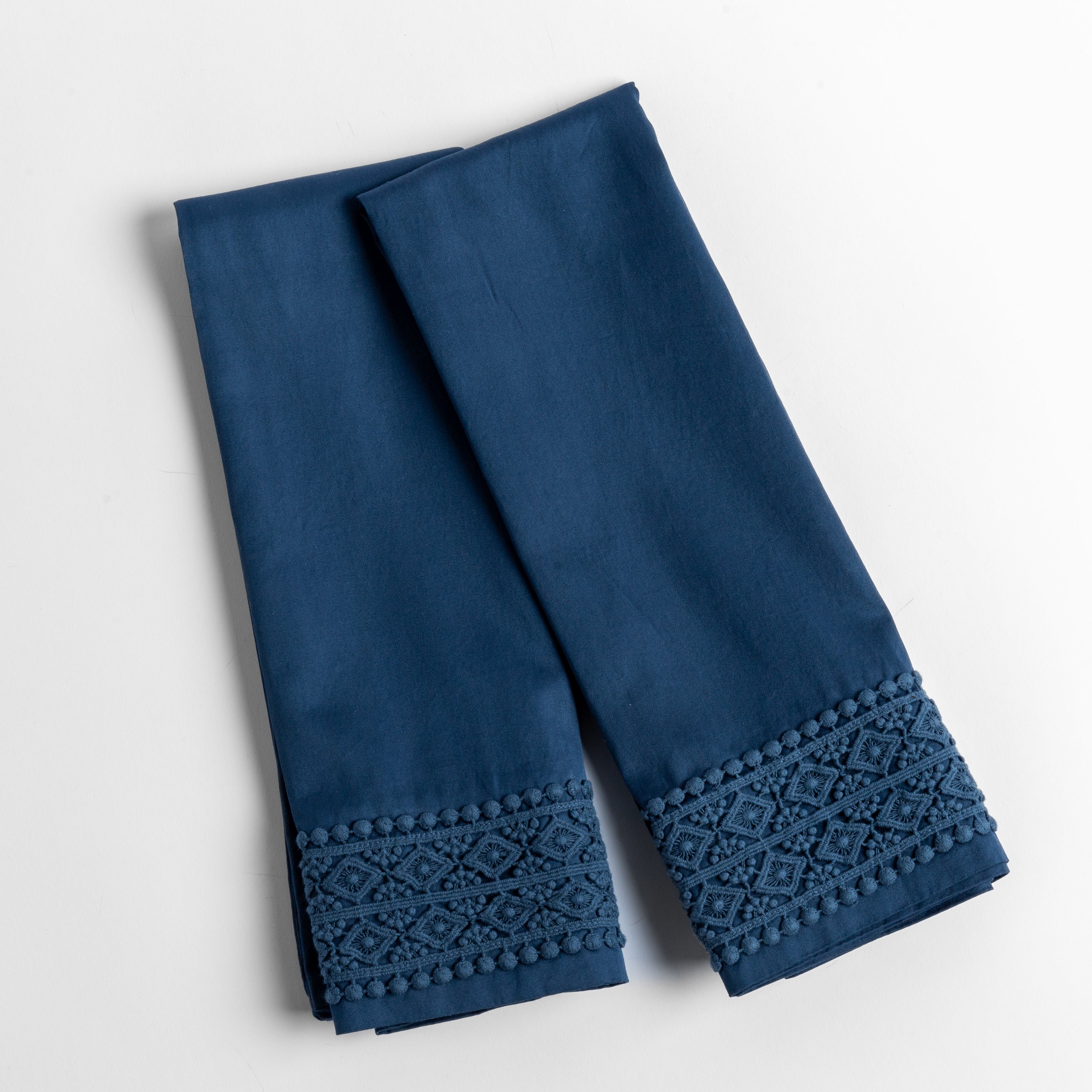 An overhead shot of a folded pair of lace trimmed pillowcases shown side by side and slightly overlapping.