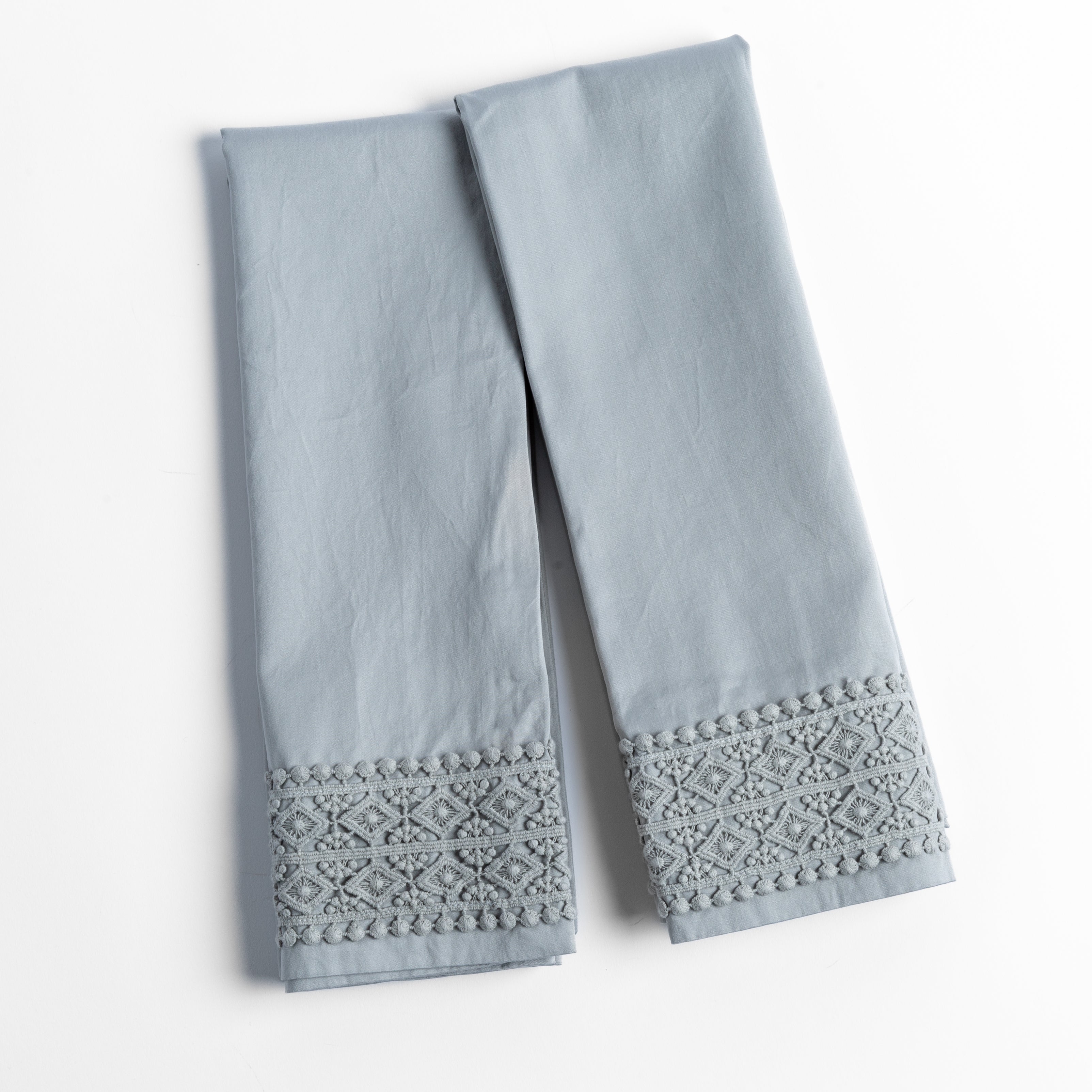 An overhead shot of a folded pair of lace trimmed pillowcases shown side by side and slightly overlapping.