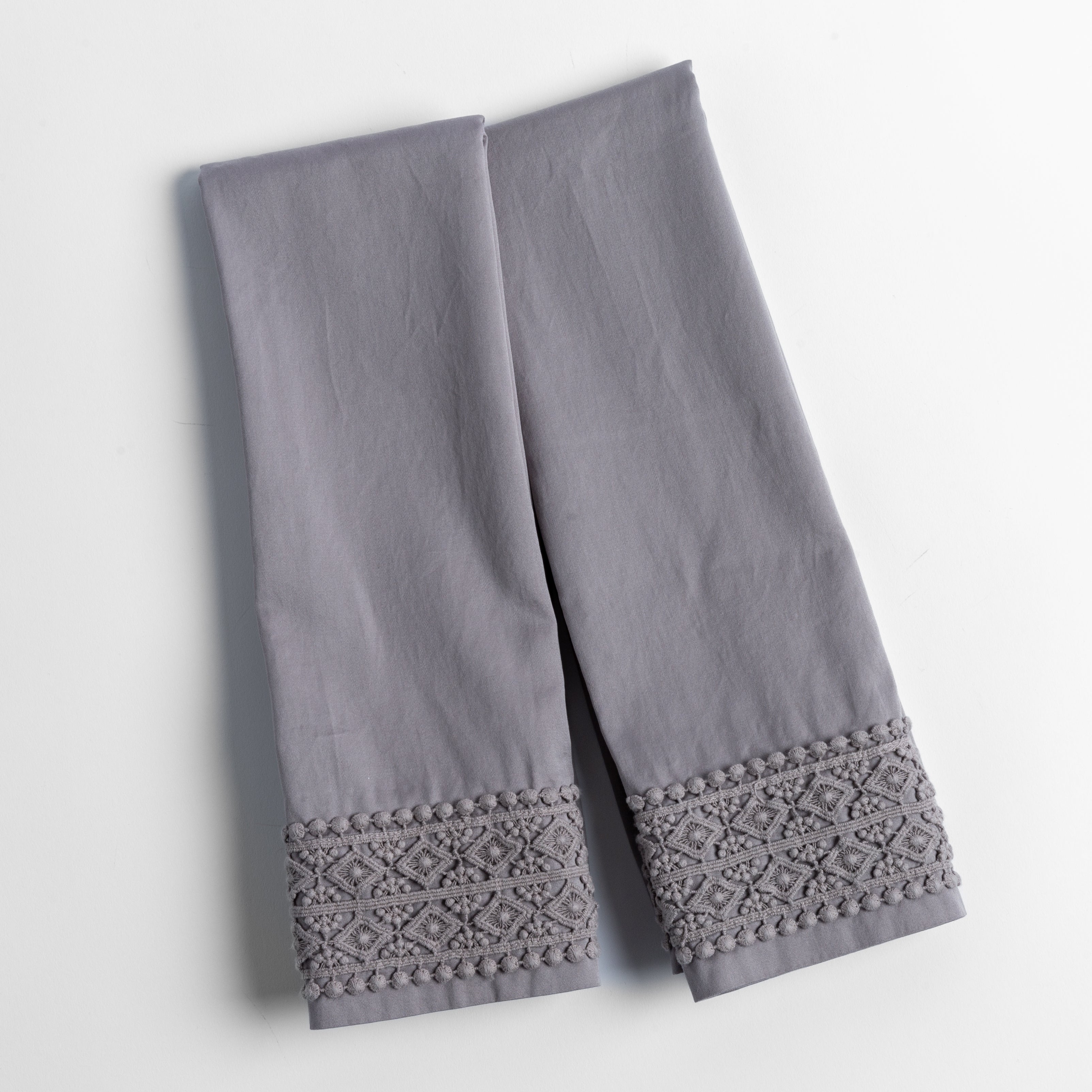 An overhead shot of a folded pair of lace trimmed pillowcases shown side by side and slightly overlapping.