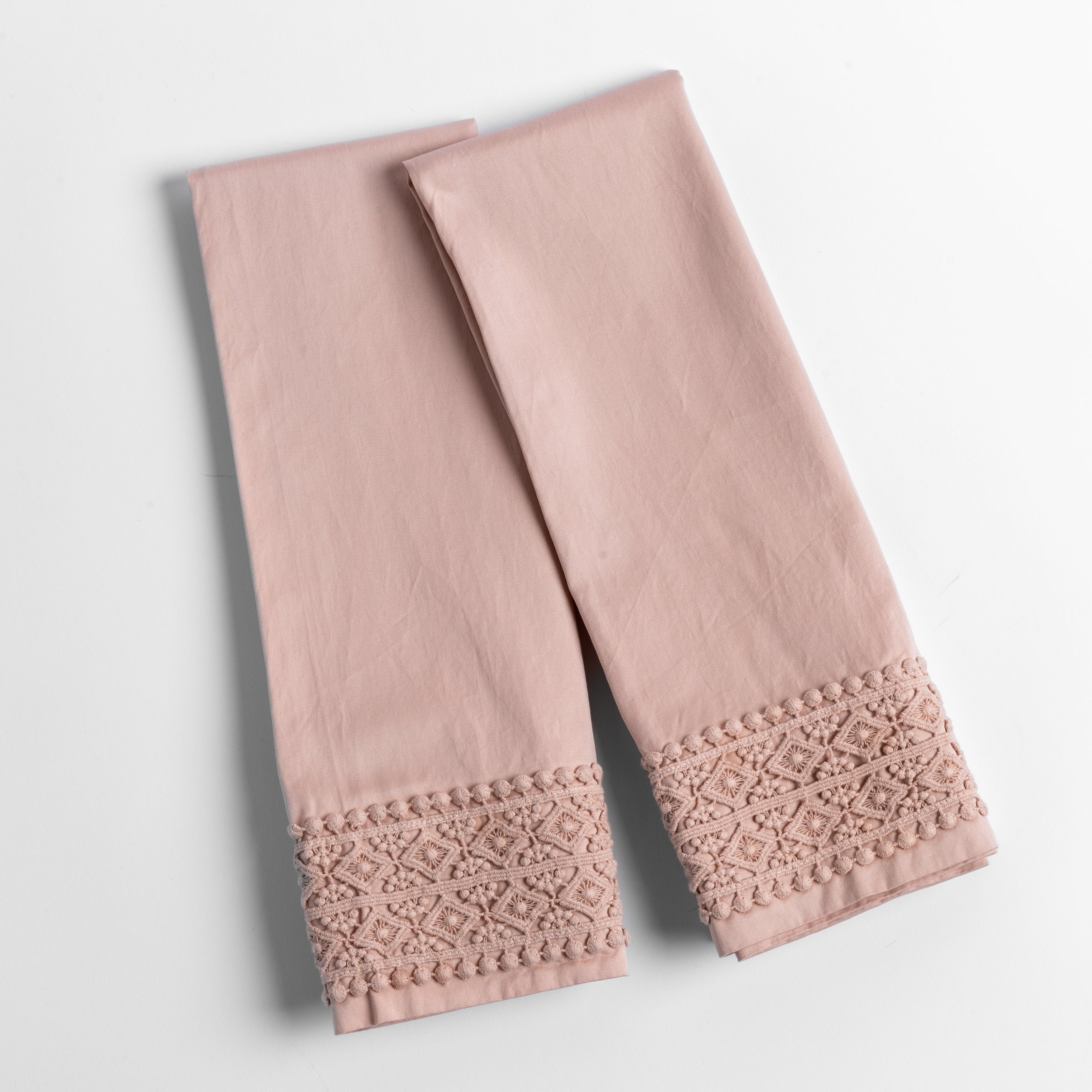 An overhead shot of a folded pair of lace trimmed pillowcases shown side by side and slightly overlapping.