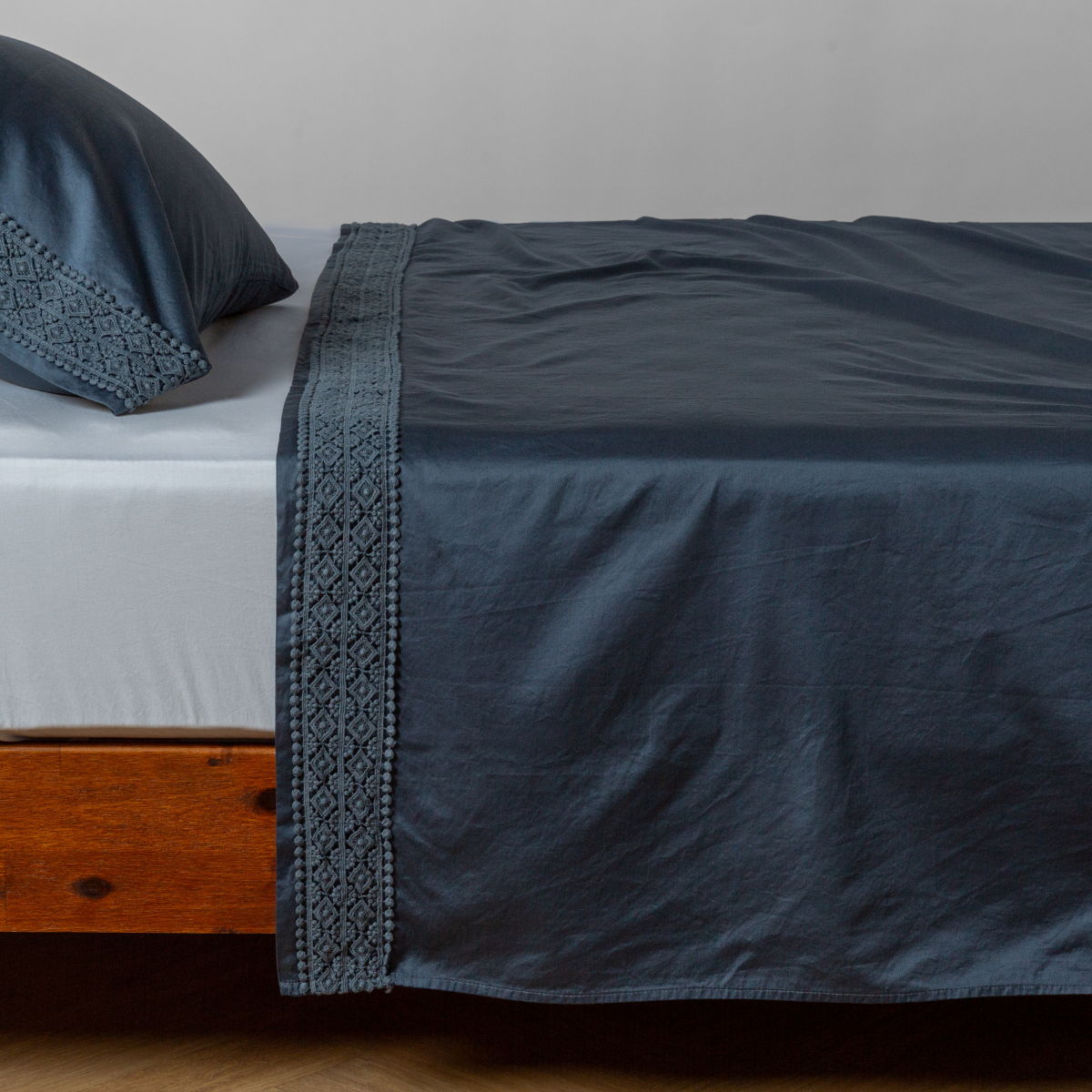 Matching lace trimmed cotton sateen flat sheet and pillowcase shown with a winter white fitted sheet - side view.