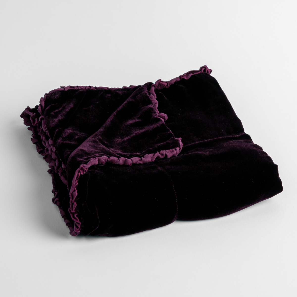 Fig: silk velvet baby blanket with charmeuse trim shown slightly overhead with a corner folded back to show trim detail against a white background.