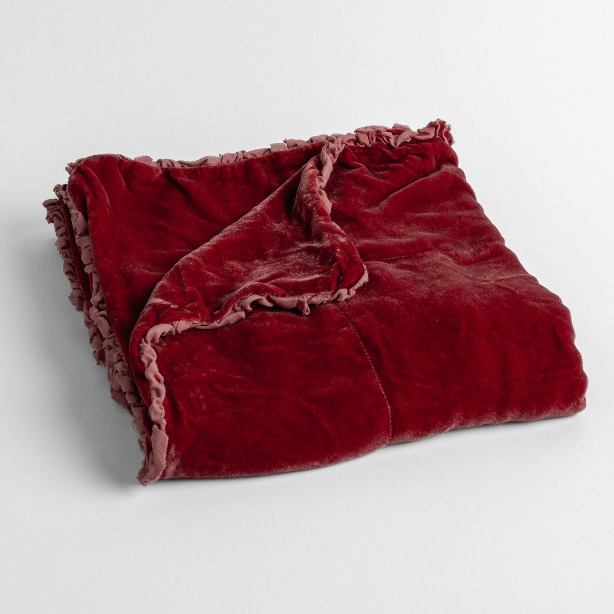 Poppy: silk velvet baby blanket with charmeuse trim shown slightly overhead with a corner folded back to show trim detail against a white background.