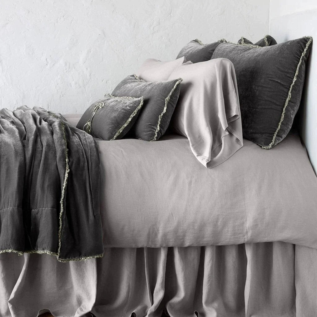 : Carmen shams in fog on monochromatic bed, leaning upright behind sleeping and throw pillows - side view.