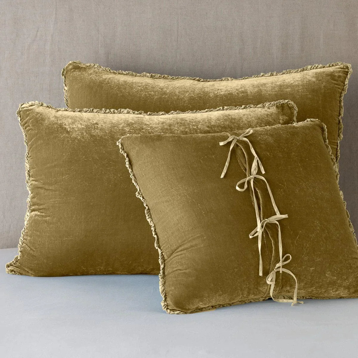 Honeycomb: Silk velvet shams with a petite ruffle leaning upright against a neutral headboard. The front sham is backwards, showcasing the charmeuse tie closures.