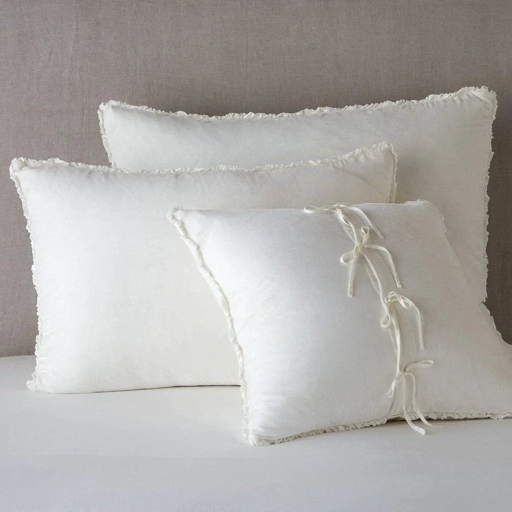 Winter White: Silk velvet shams with a petite ruffle leaning upright against a neutral headboard. The front sham is backwards, showcasing the charmeuse tie closures.